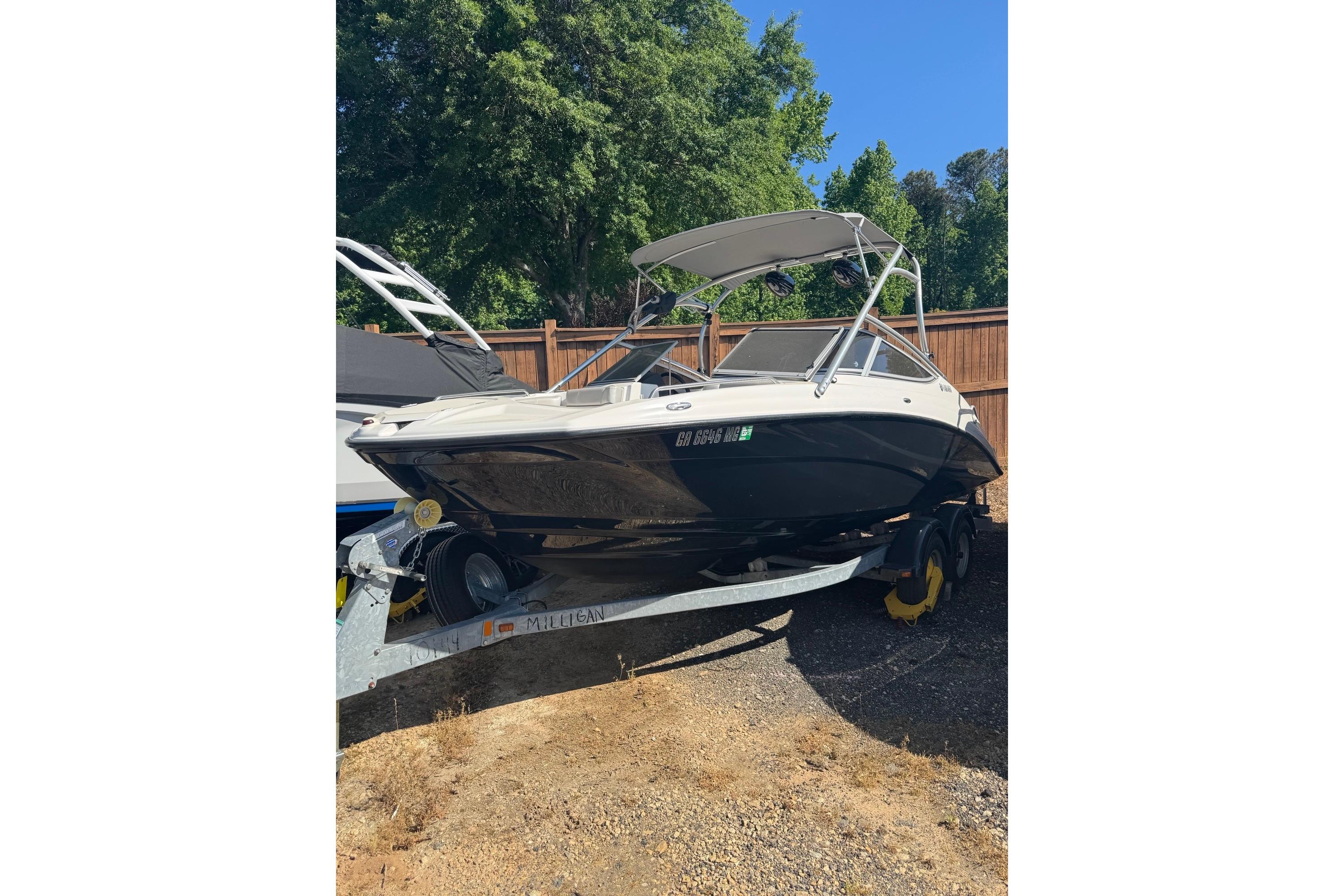 2012 Yamaha AR210 boat on trailer, parked outdoors near wooden fence.
