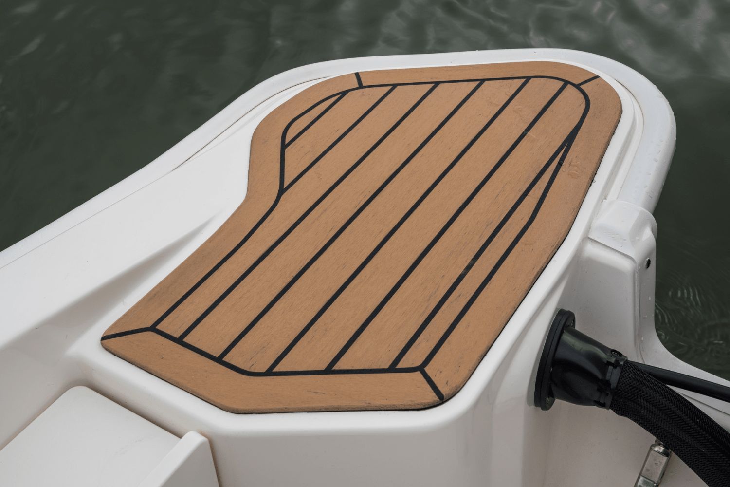 Close-up of a boat deck with wood-like finish and black lines.
