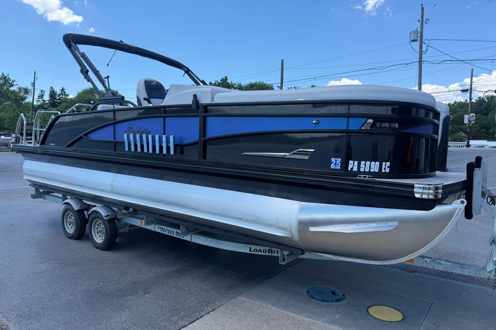 2023 Barletta Corsa 23U pontoon boat on trailer, blue and black design, parked outdoors.