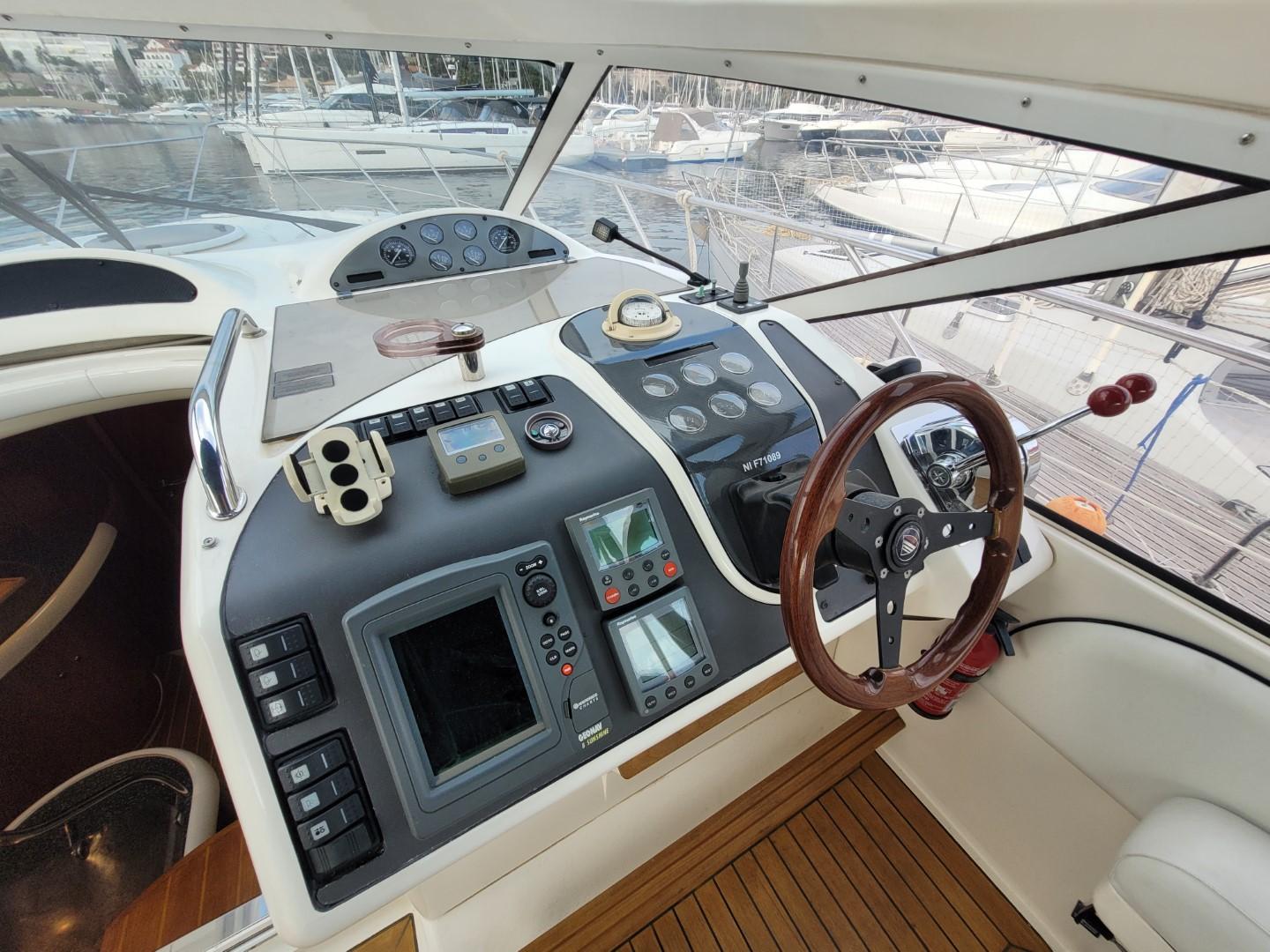 2004 Fairline Targa 43 yacht helm with navigation controls and wooden steering wheel.