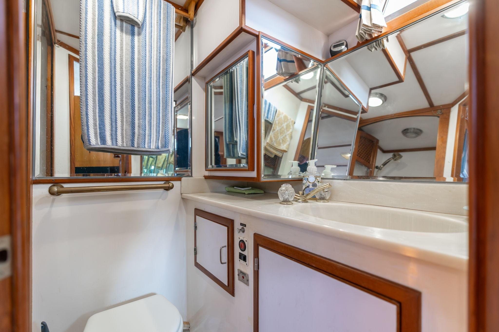 Bathroom interior of 1991 Lien Hwa Cockpit Sundeck yacht with mirrors and striped towel.