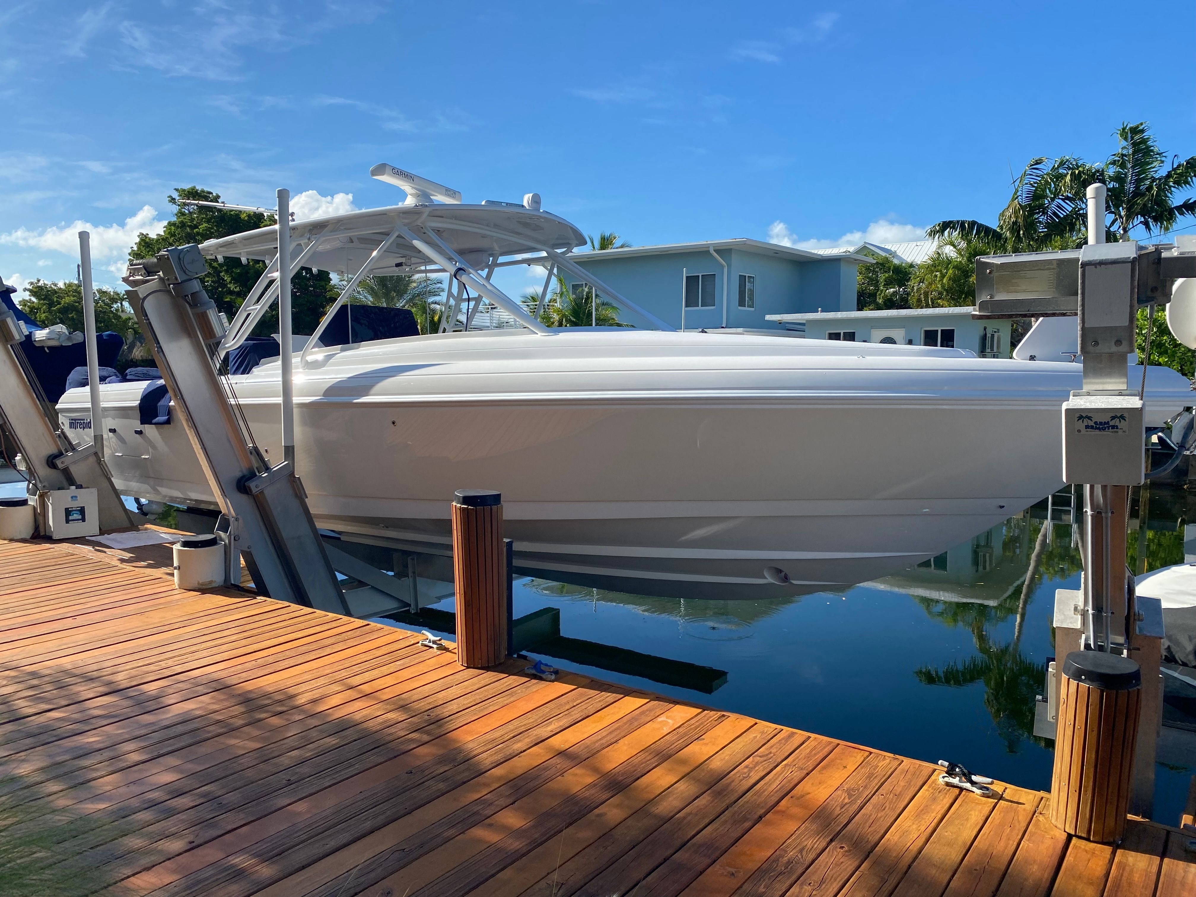 A 2011 Intrepid 37 boat is docked at a wooden pier in a calm harbor.