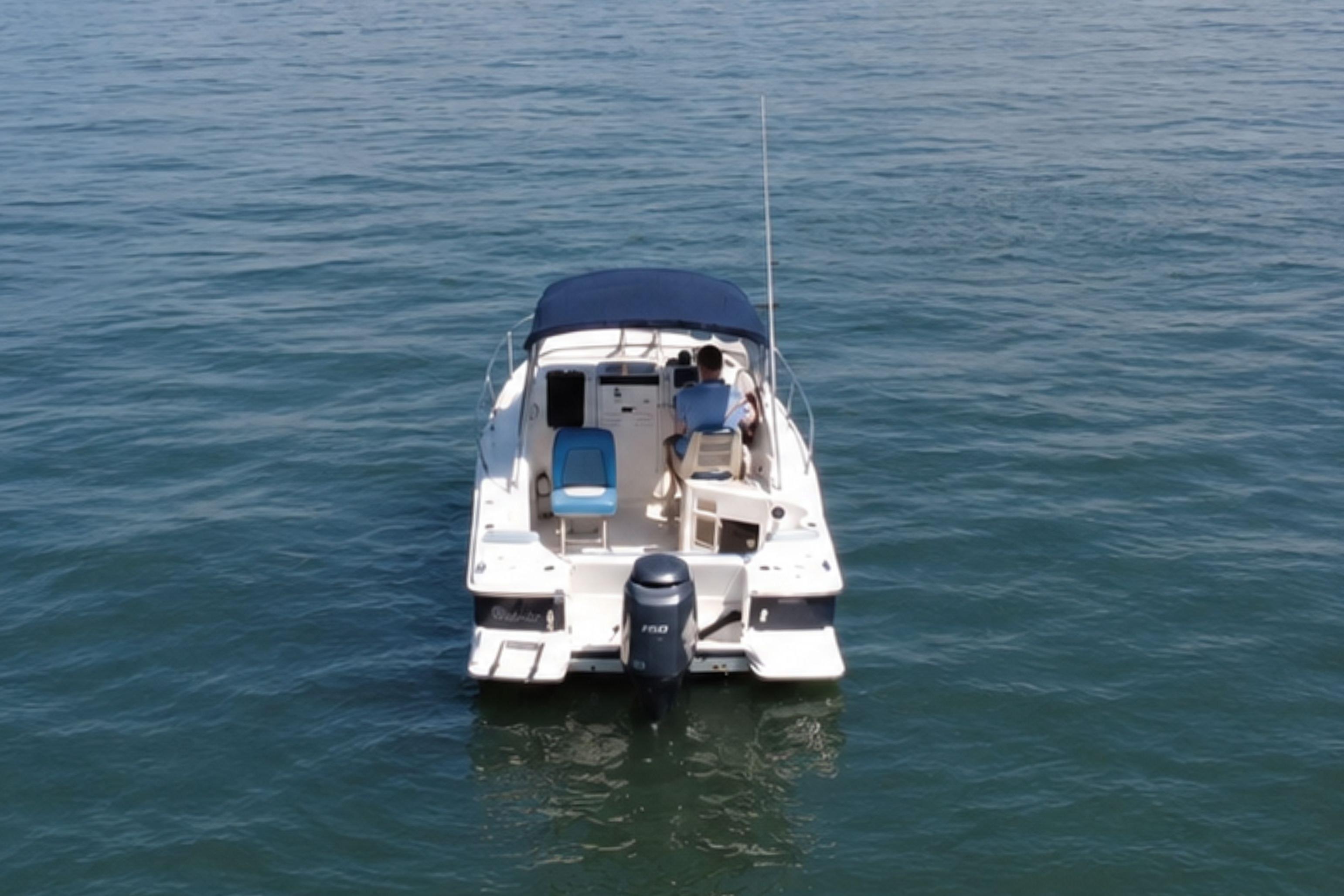 2008 Scout 222 Abaco boat on calm water, rear view with blue canopy.
