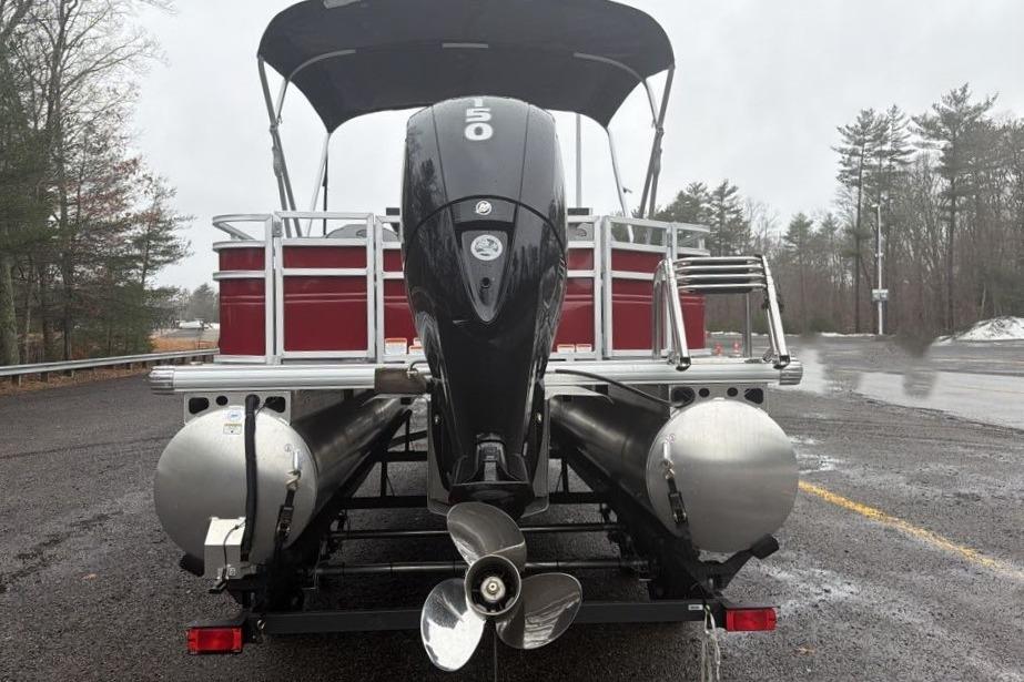 2026 Sun Tracker SportFish 22 DLX pontoon boat with powerful outboard motor on a rainy day.