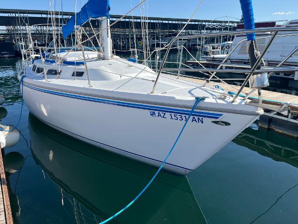 1980 Catalina 30 sailboat docked in marina, featuring white hull and blue accents.