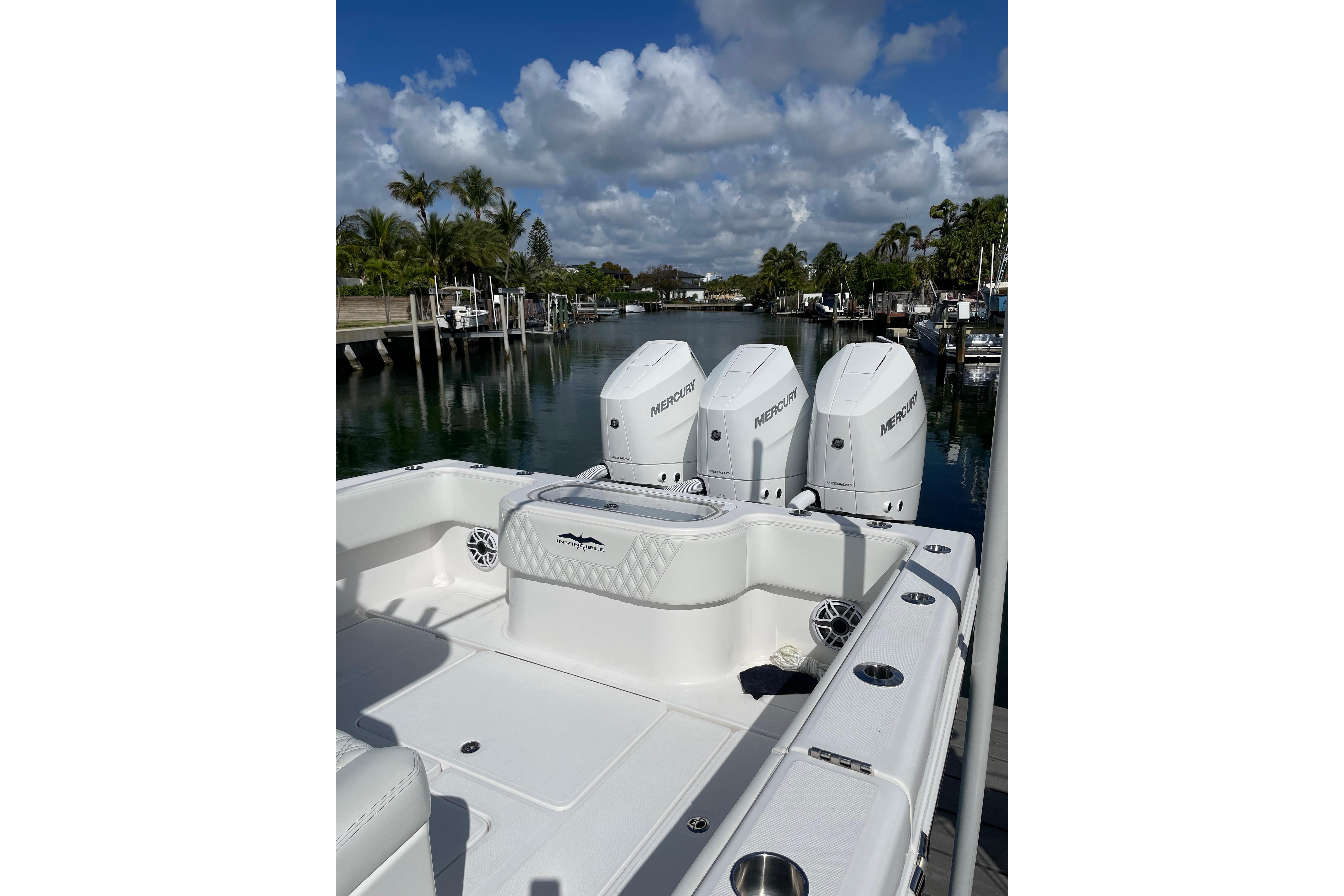 2024 Invincible 36 Open Fisherman boat with triple Mercury engines docked by a serene waterfront.