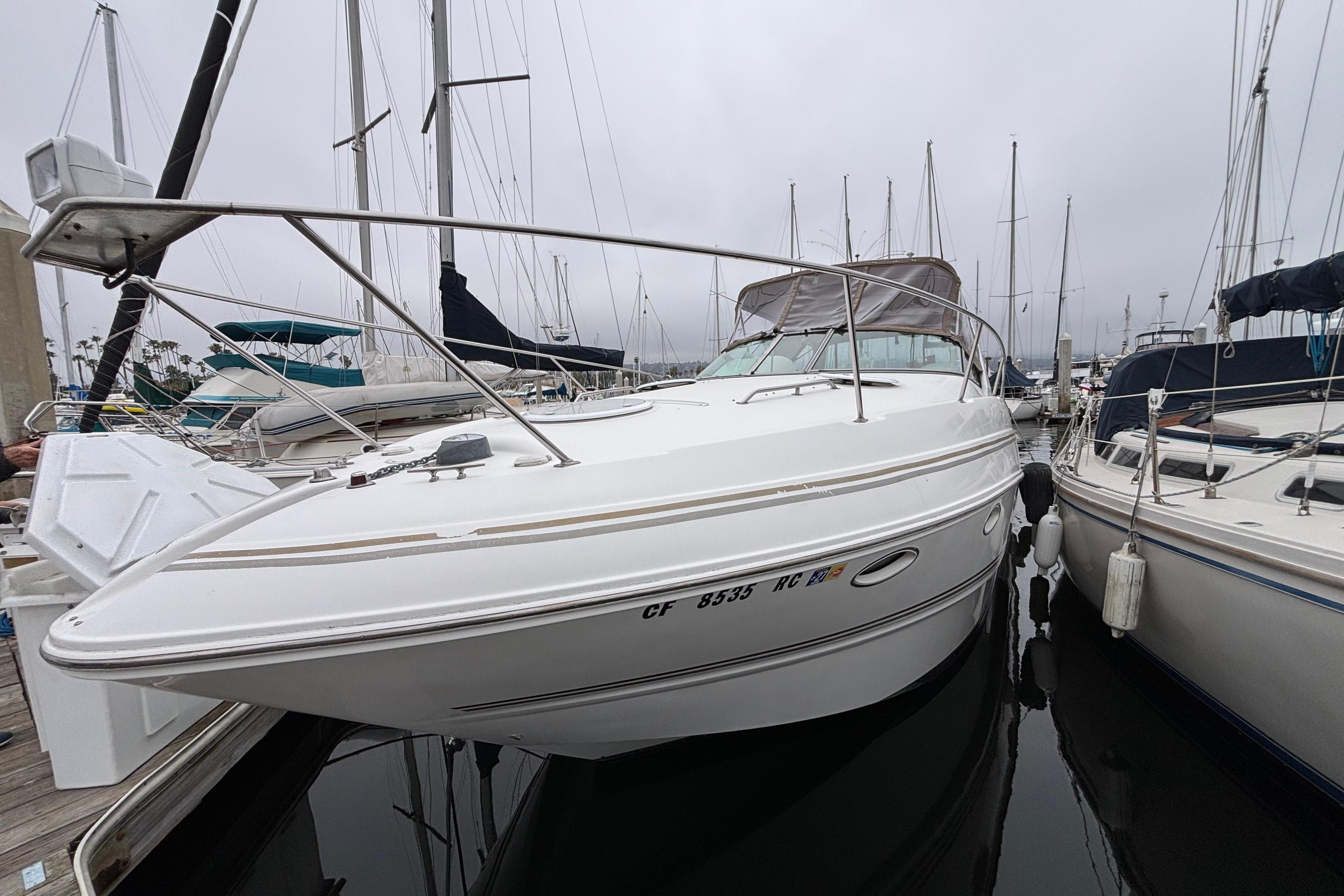 2004 Larson 310 boat docked at marina, surrounded by other sailboats.