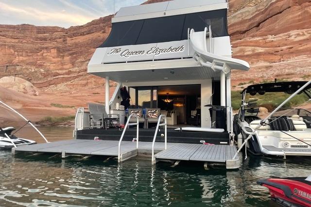 Luxury houseboat "The Queen Elizabeth" by Adonia, 2021, docked on serene waters with scenic rock backdrop.