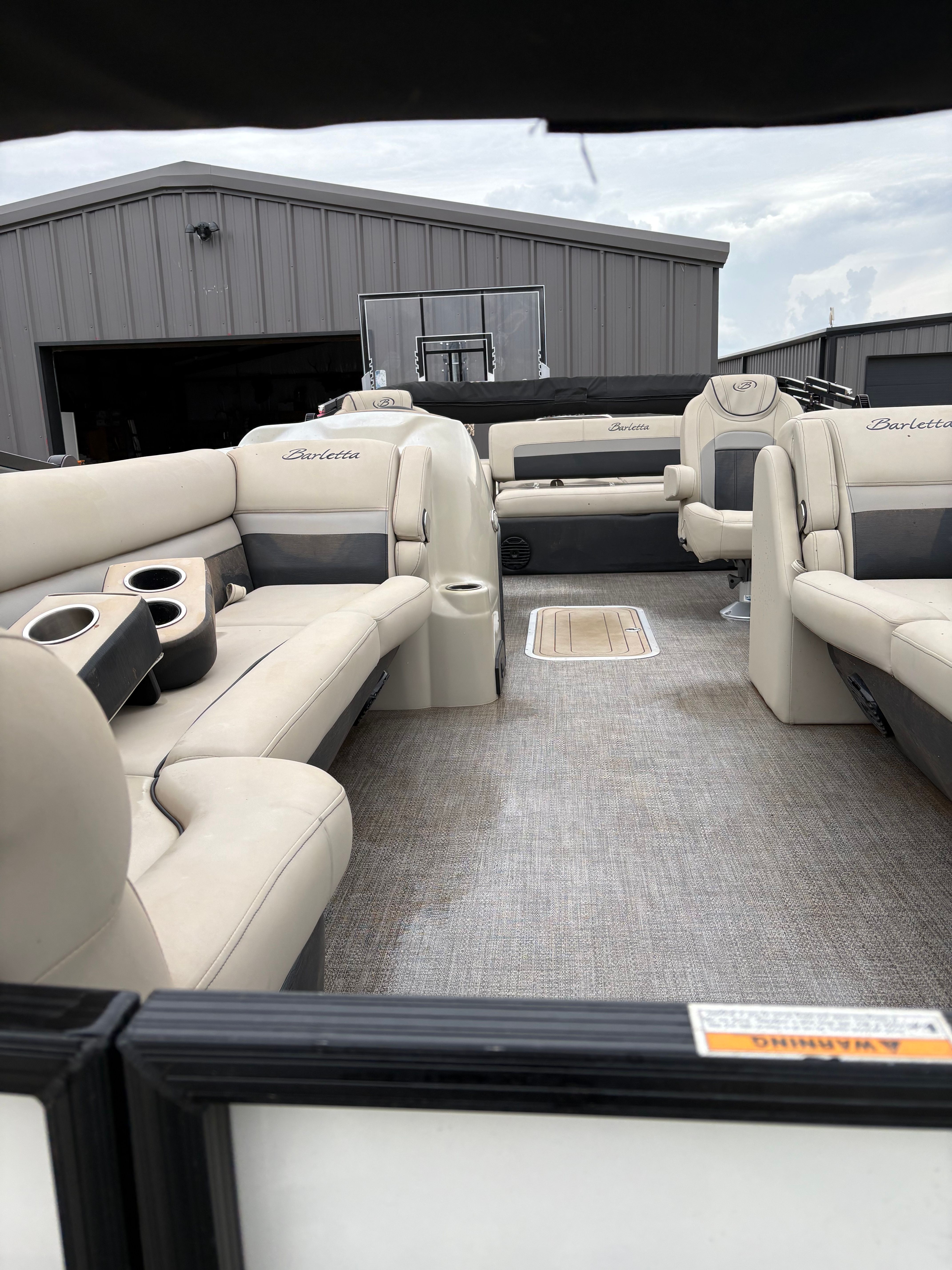 Interior of a Barletta C24UC pontoon boat with beige seating and gray flooring.