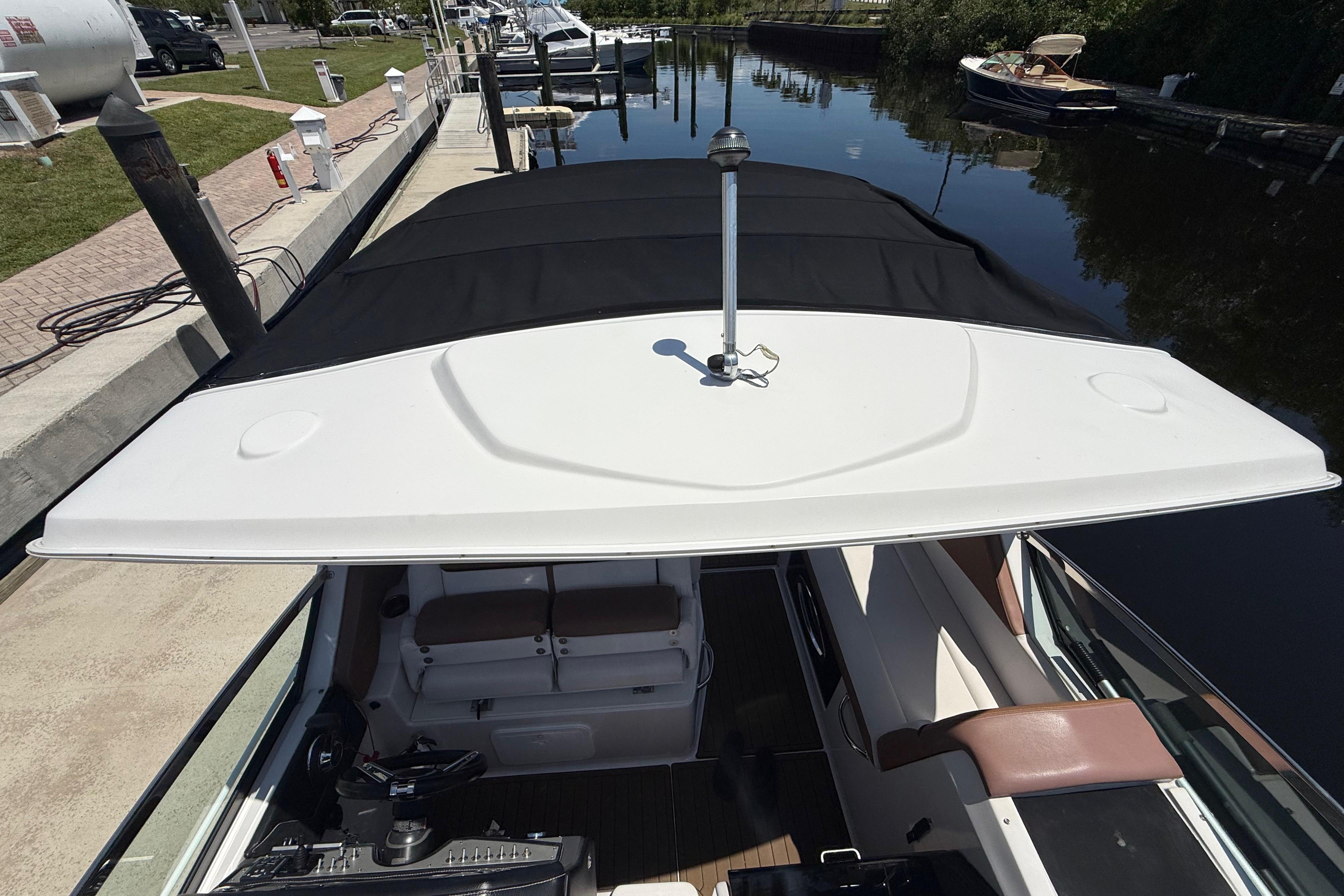 2017 Four Winns V275 boat docked, featuring a covered cockpit and sleek design.