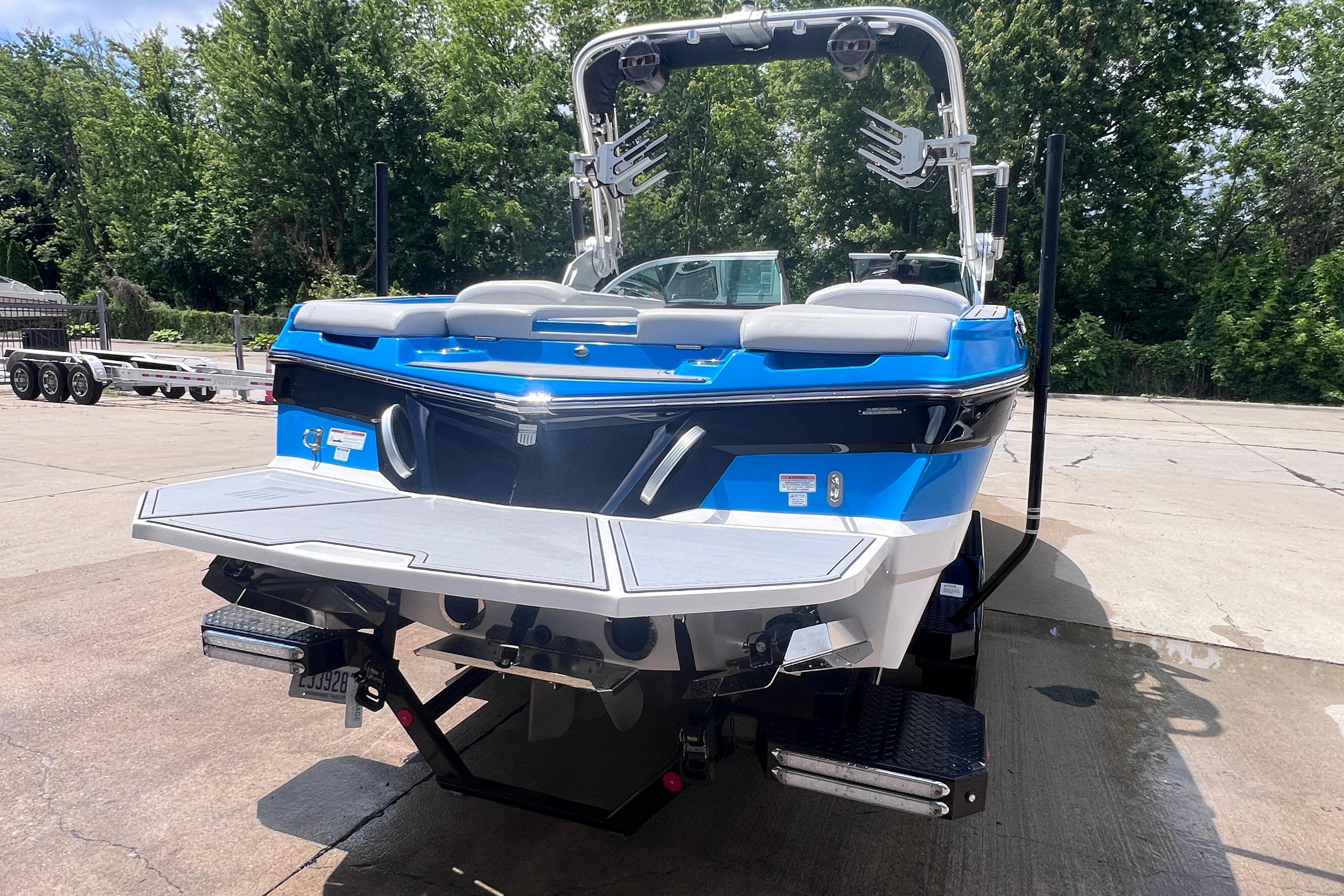 2021 MasterCraft XT23 boat with blue and white exterior, parked on a concrete surface.