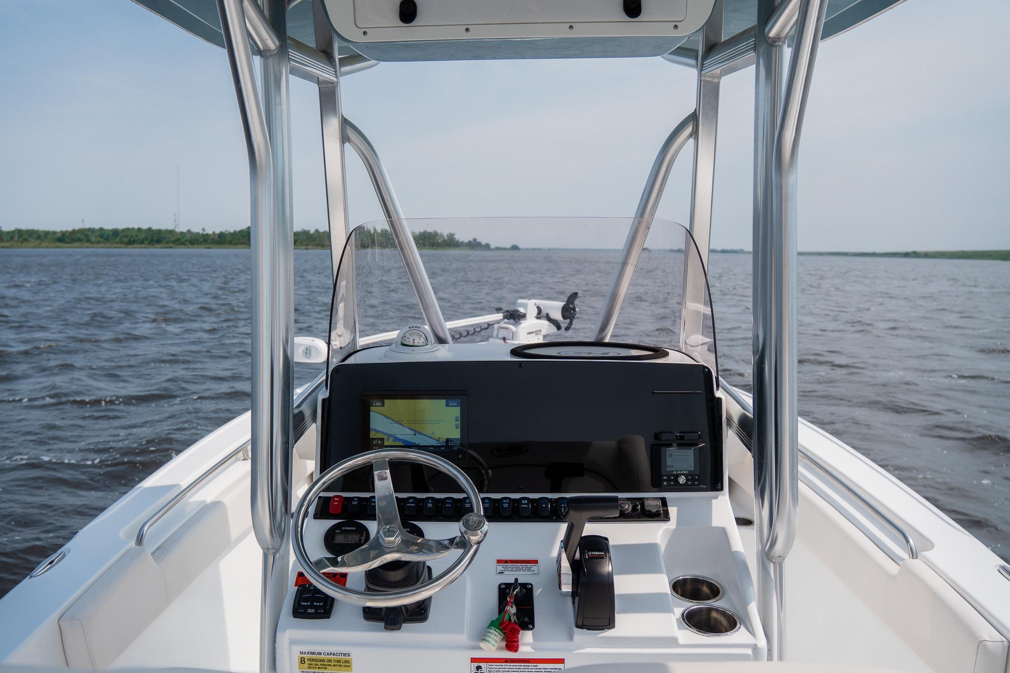 2022 Sea Hunt Ultra 229 boat dashboard with steering wheel and navigation system on open water.