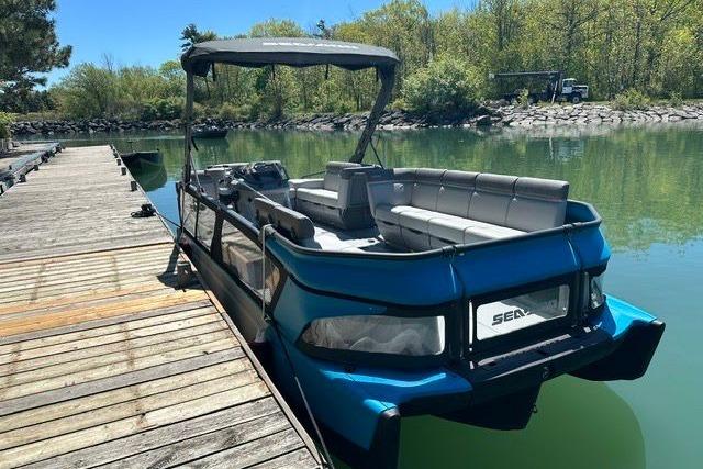 2023 Sea Doo SWITCH CRUISE docked on a serene lake with lush greenery.