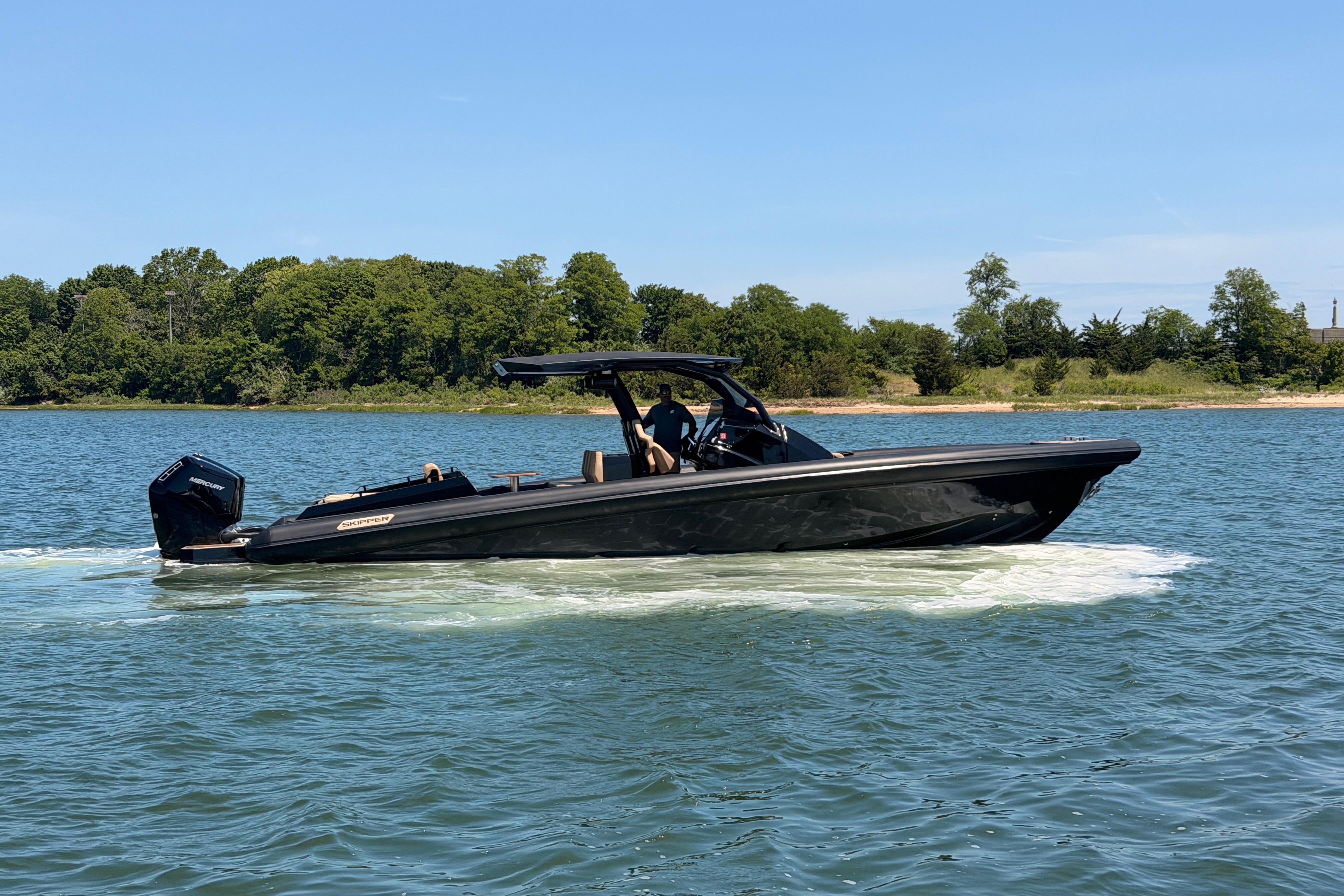 2023 Skipper-BSK 42NC boat cruising on a serene lake with lush green shoreline.