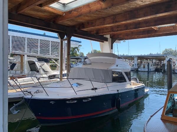 2021 Cutwater C-32 CB boat docked in a marina under a wooden shelter.