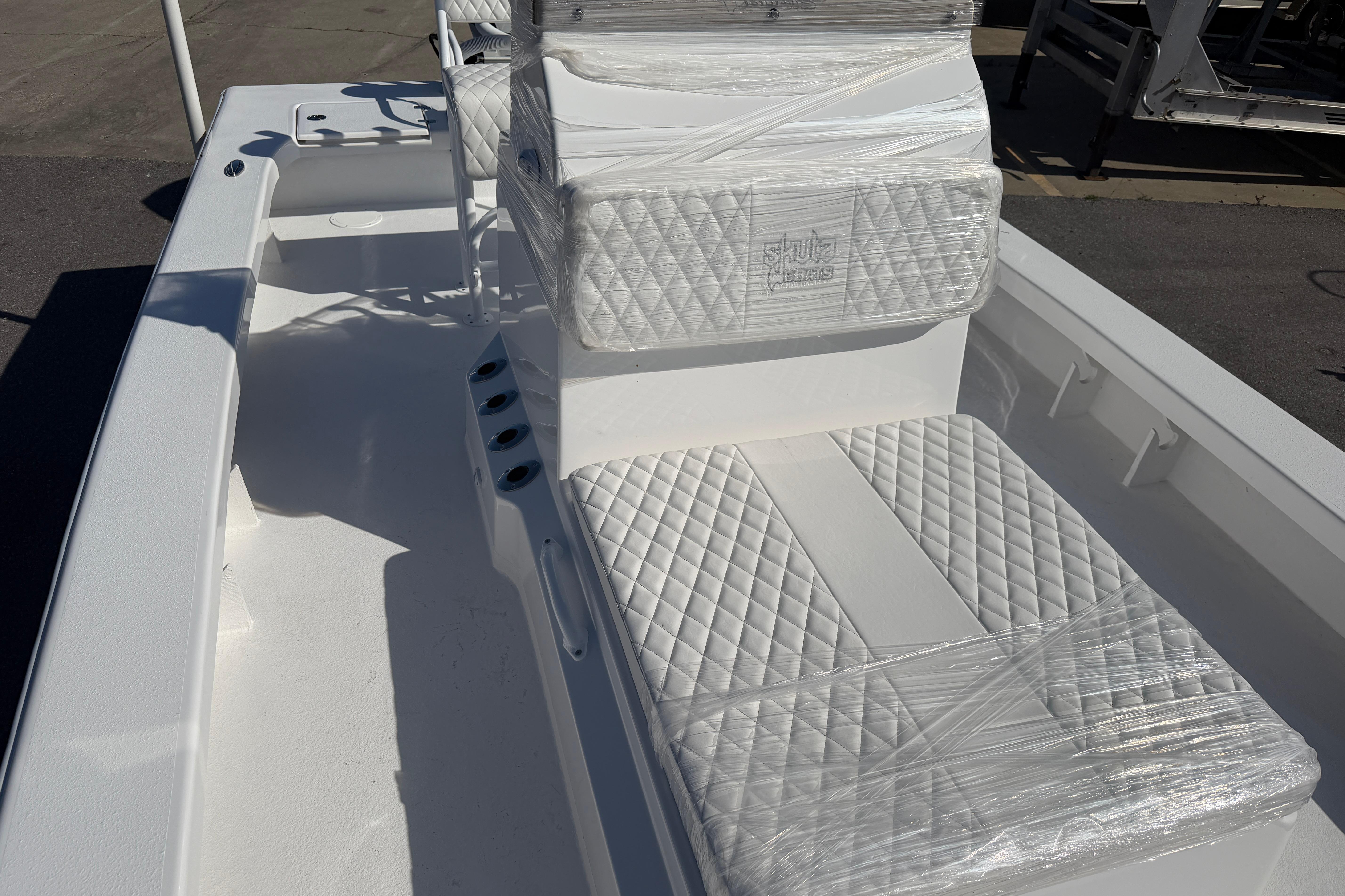 2026 Skuta 24 Cat boat interior with wrapped, quilted seats and rod holders.