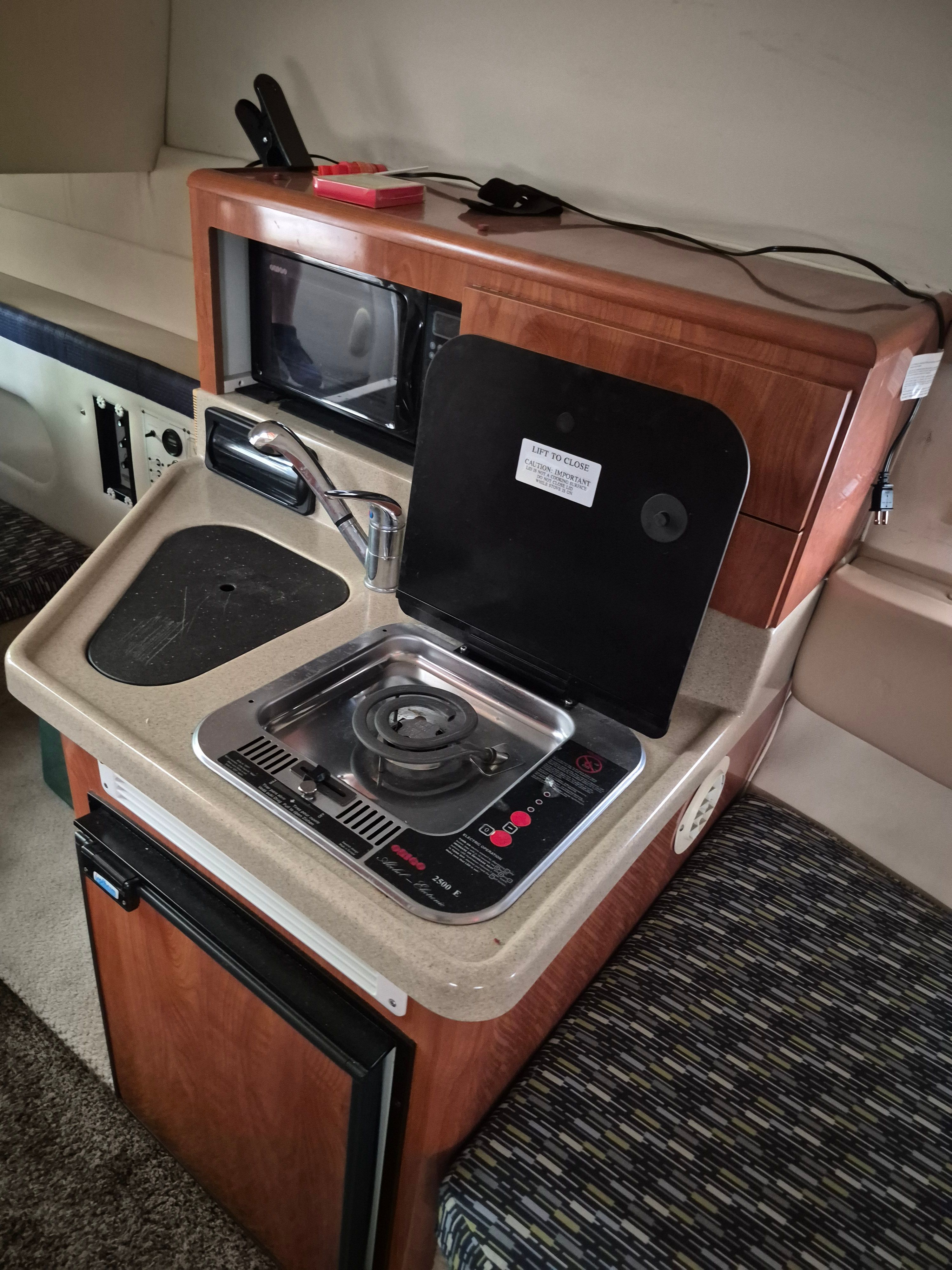 The galley of a 2004 Larson Cabrio 274 with stove, sink, and microwave.