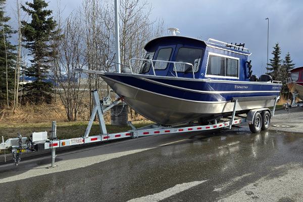 2024 Spartan 26 Maximus Pro XL boat on trailer, parked on wet road.
