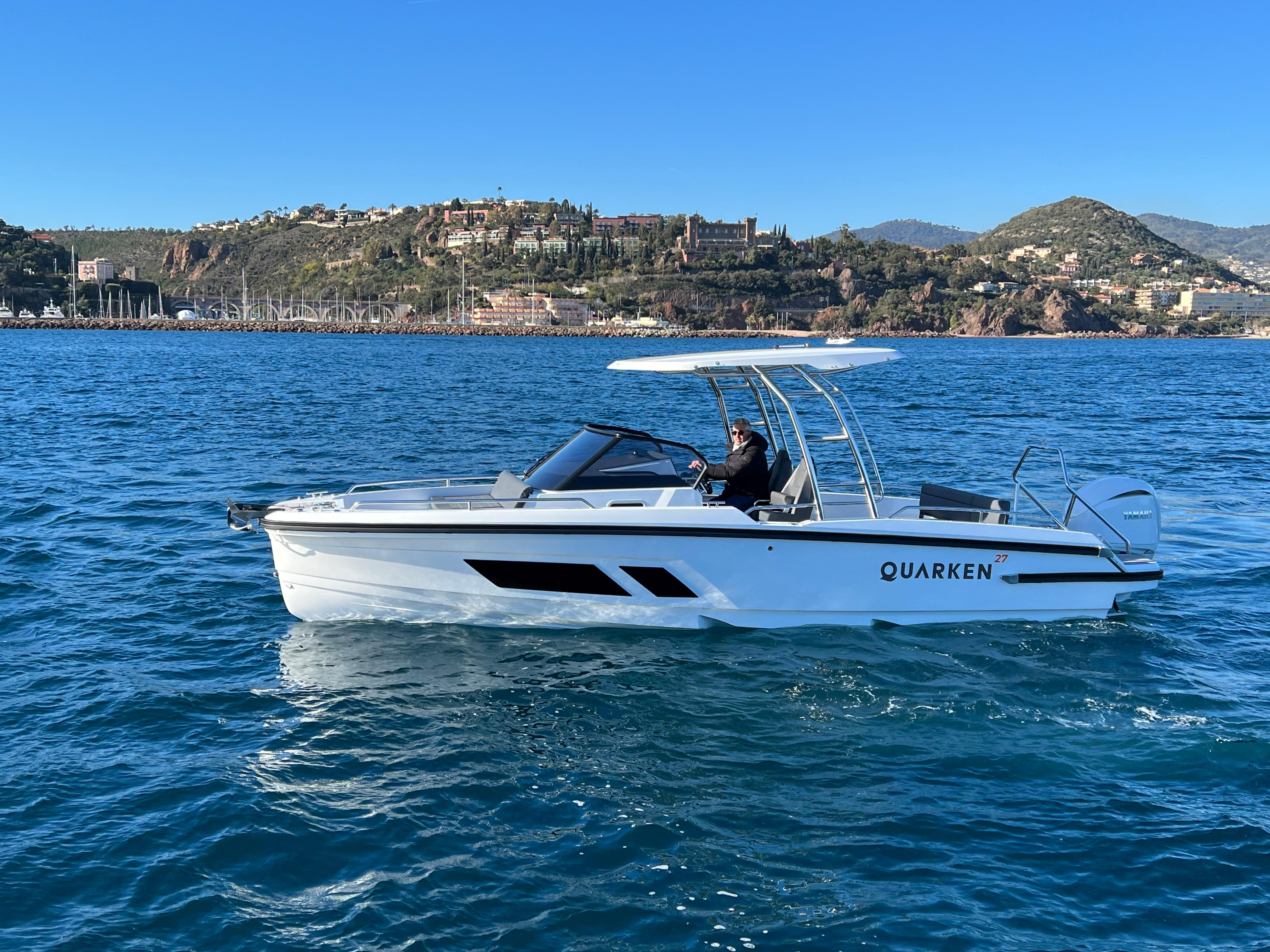 2025 Quarken 27 T-Top boat cruising on blue water with scenic coastal backdrop.
