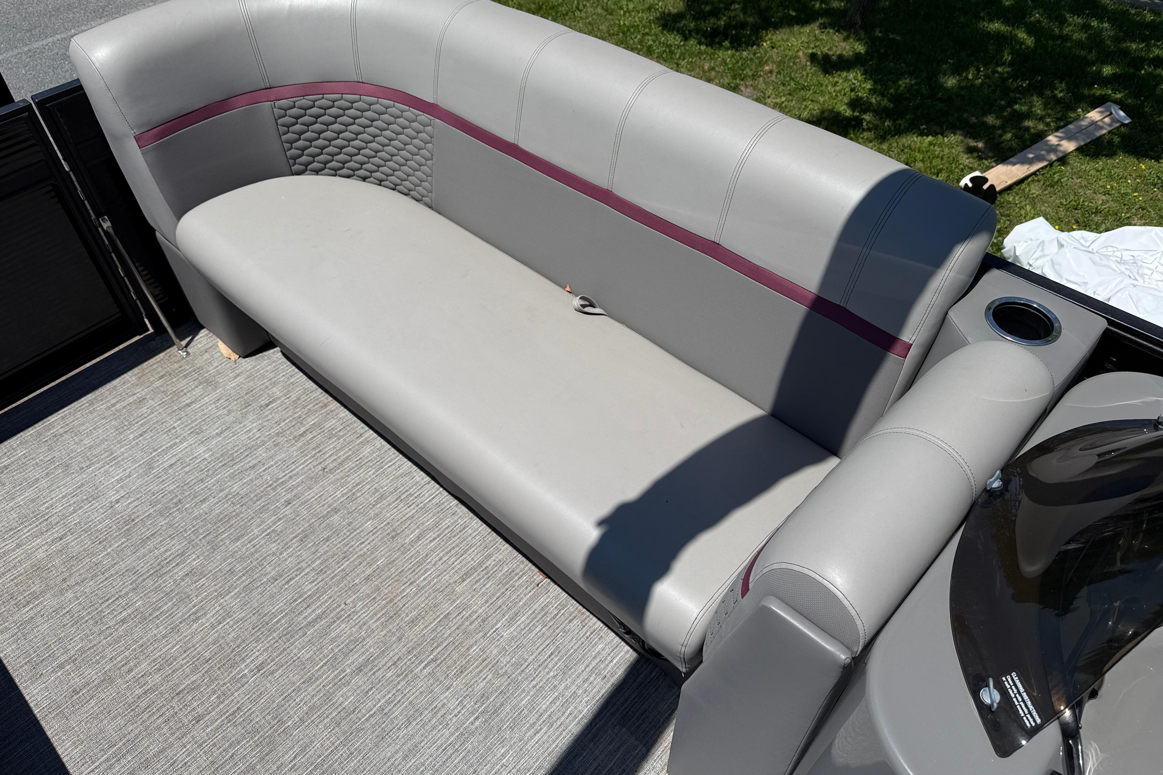 Gray seating area on 2023 Apex 818 boat, featuring cup holder and textured upholstery.