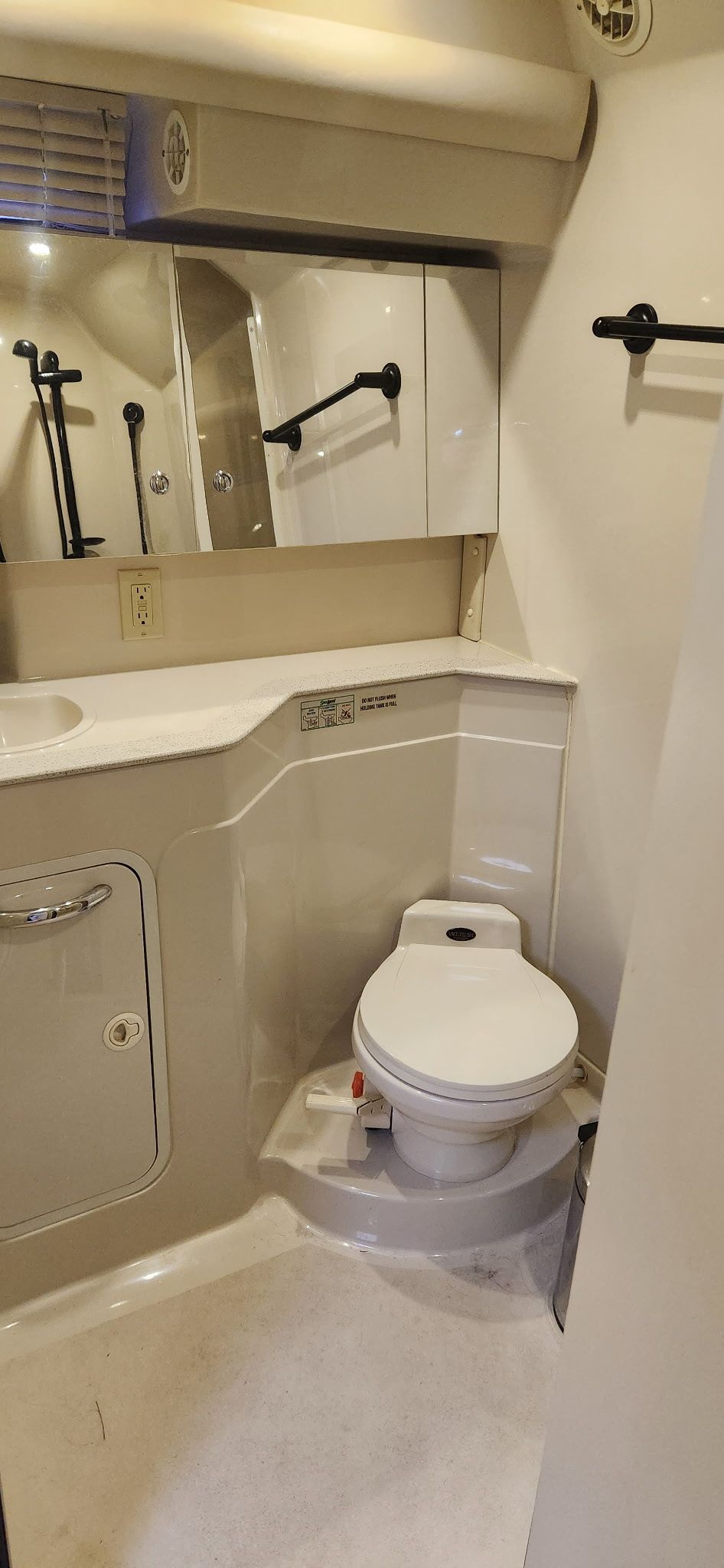 A yacht bathroom with a toilet, sink, and mirror.