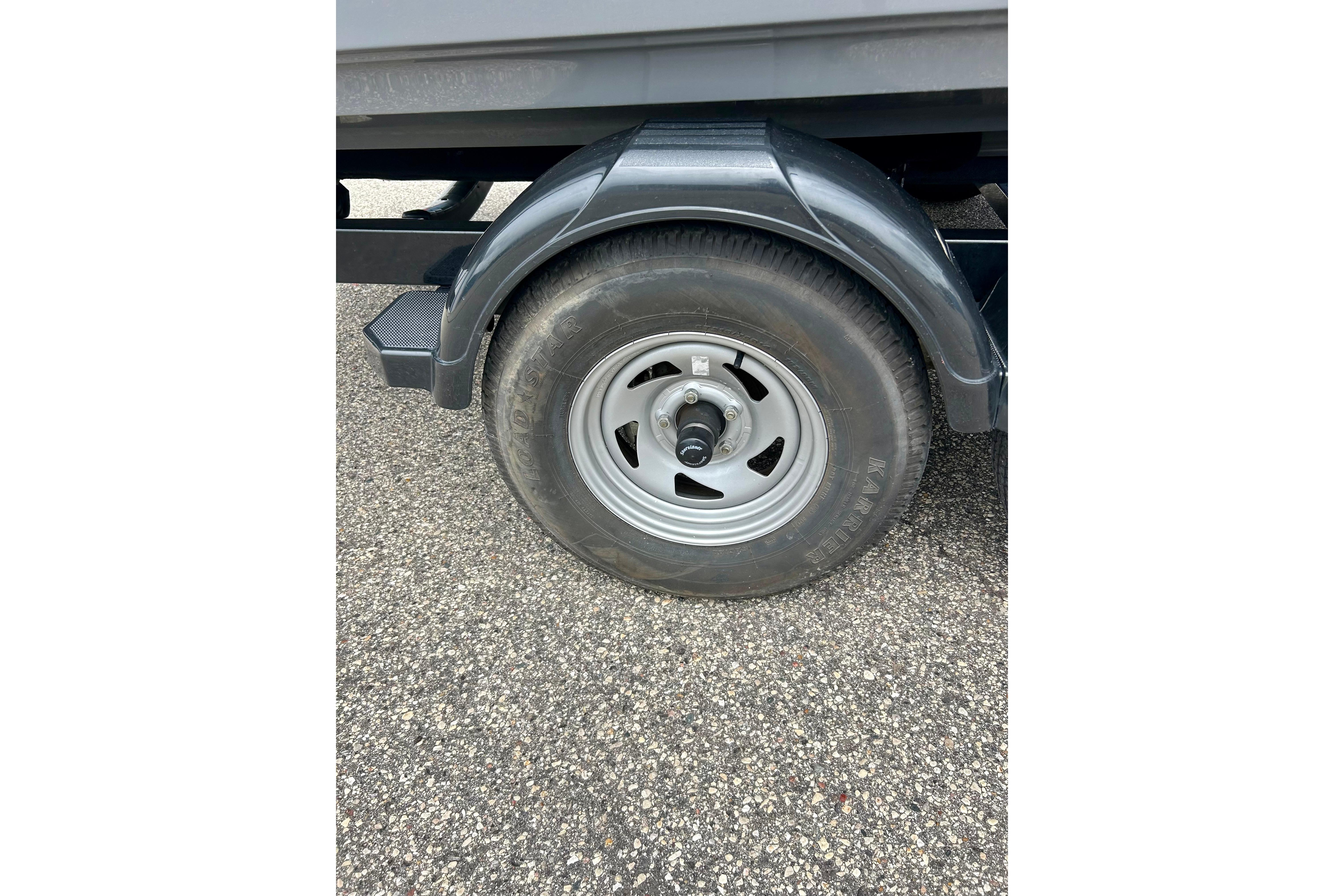 Trailer wheel of a 2015 Yamaha Boats AR210 on asphalt surface.