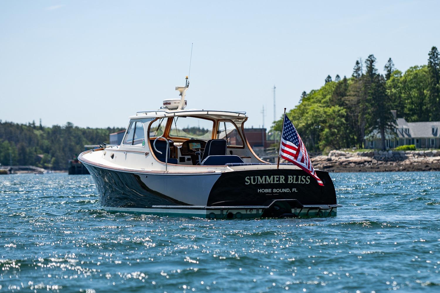 2001 Hinckley Picnic Boat 36 Classic on water, American flag, scenic background.