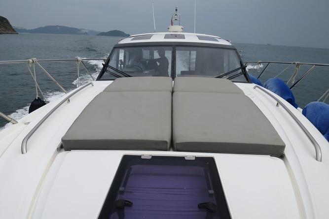 2016 Princess V48 yacht cruising on open water with sunbathing cushions on deck.