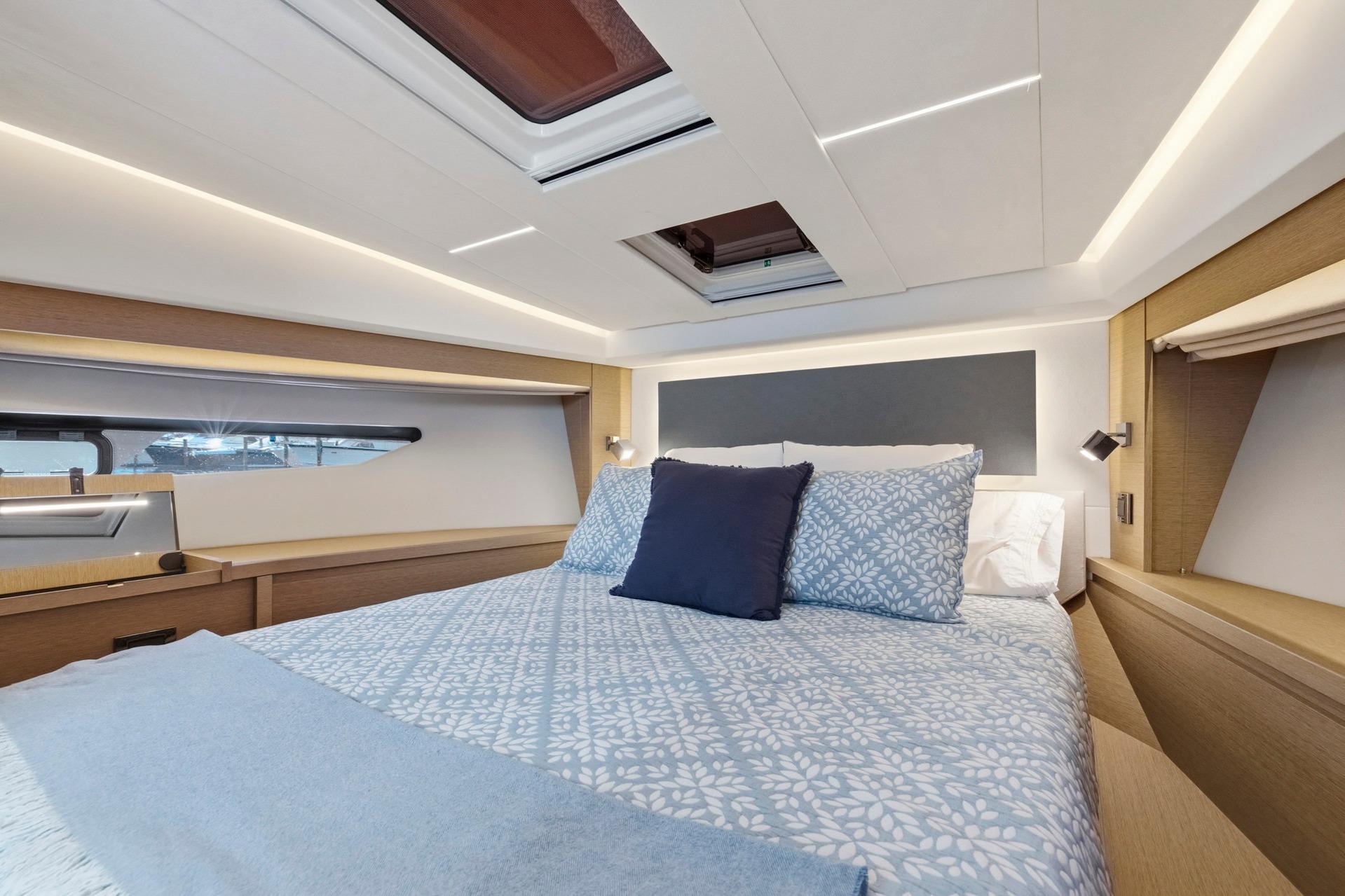 Luxurious cabin interior of 2022 Prestige 520 yacht with elegant bedding and modern lighting.