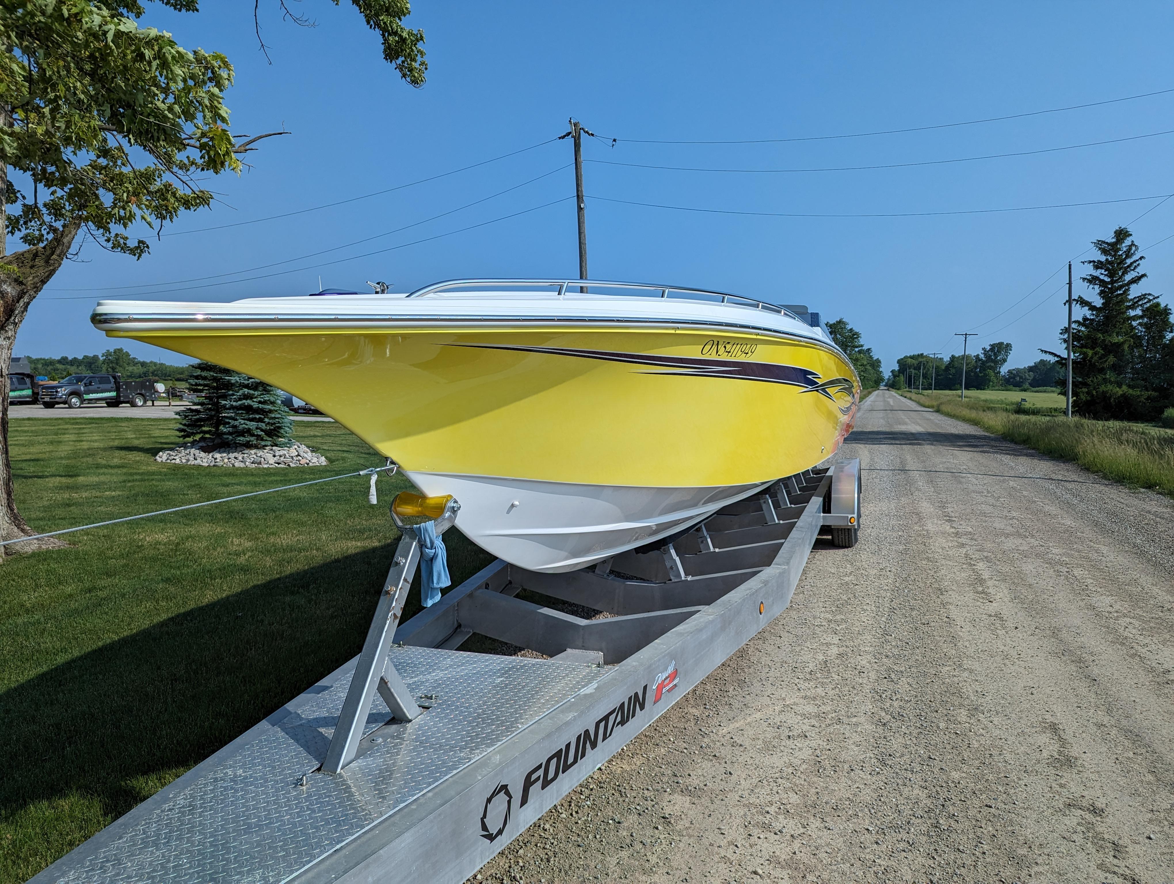 Yellow 2006 Fountain 42 boat on trailer, parked on rural road.
