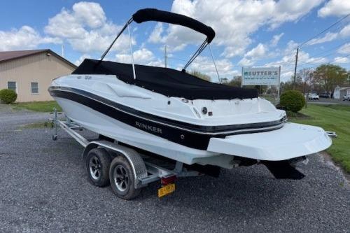 2017 Rinker QX21 BR boat on trailer, black and white design, parked outdoors under blue sky.