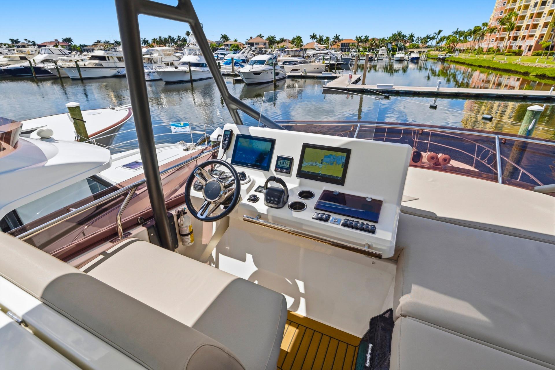 Cockpit view of 2022 Prestige 520 yacht at marina, featuring modern navigation equipment.