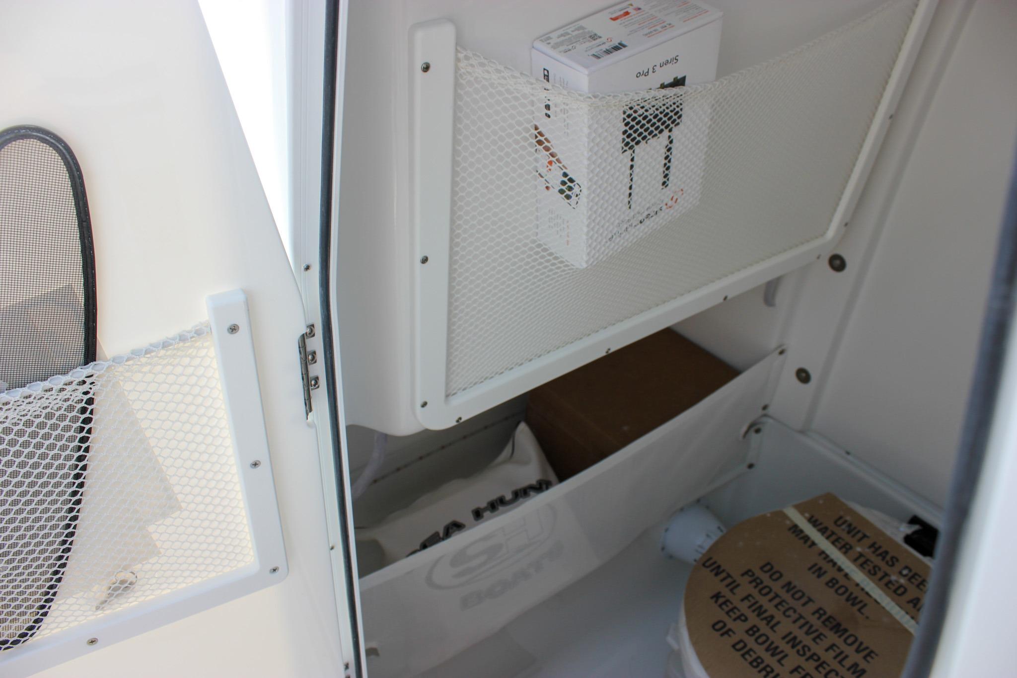 Storage compartment inside 2027 Sea Hunt Ultra 275 SE boat, featuring netted pockets and organized items.