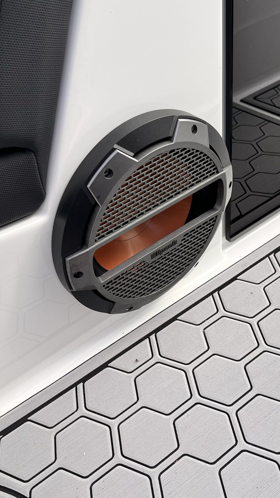 Close-up of a speaker on a boat with hexagonal flooring.