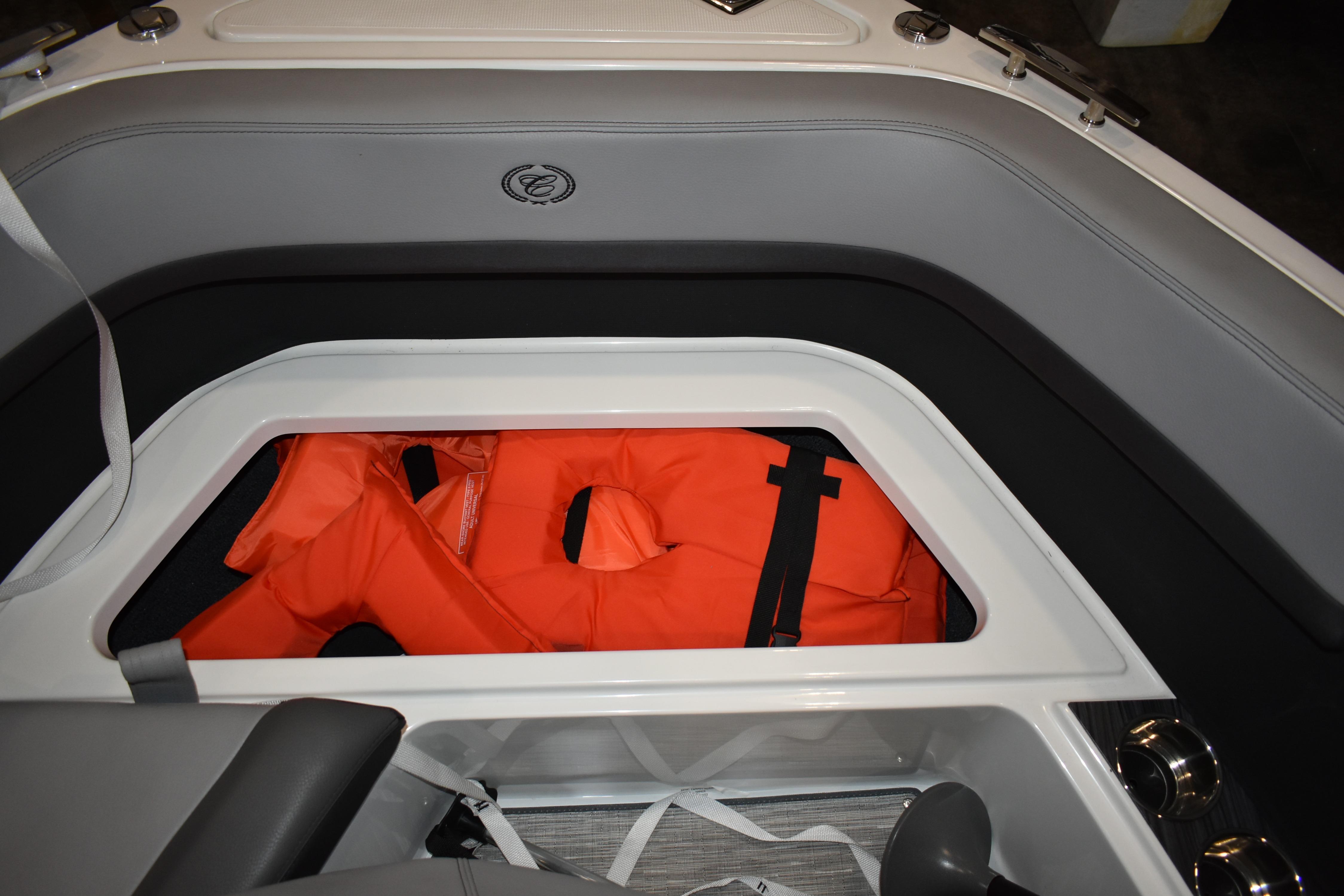 Storage compartment in 2023 Cobalt R8 boat with orange life jackets.