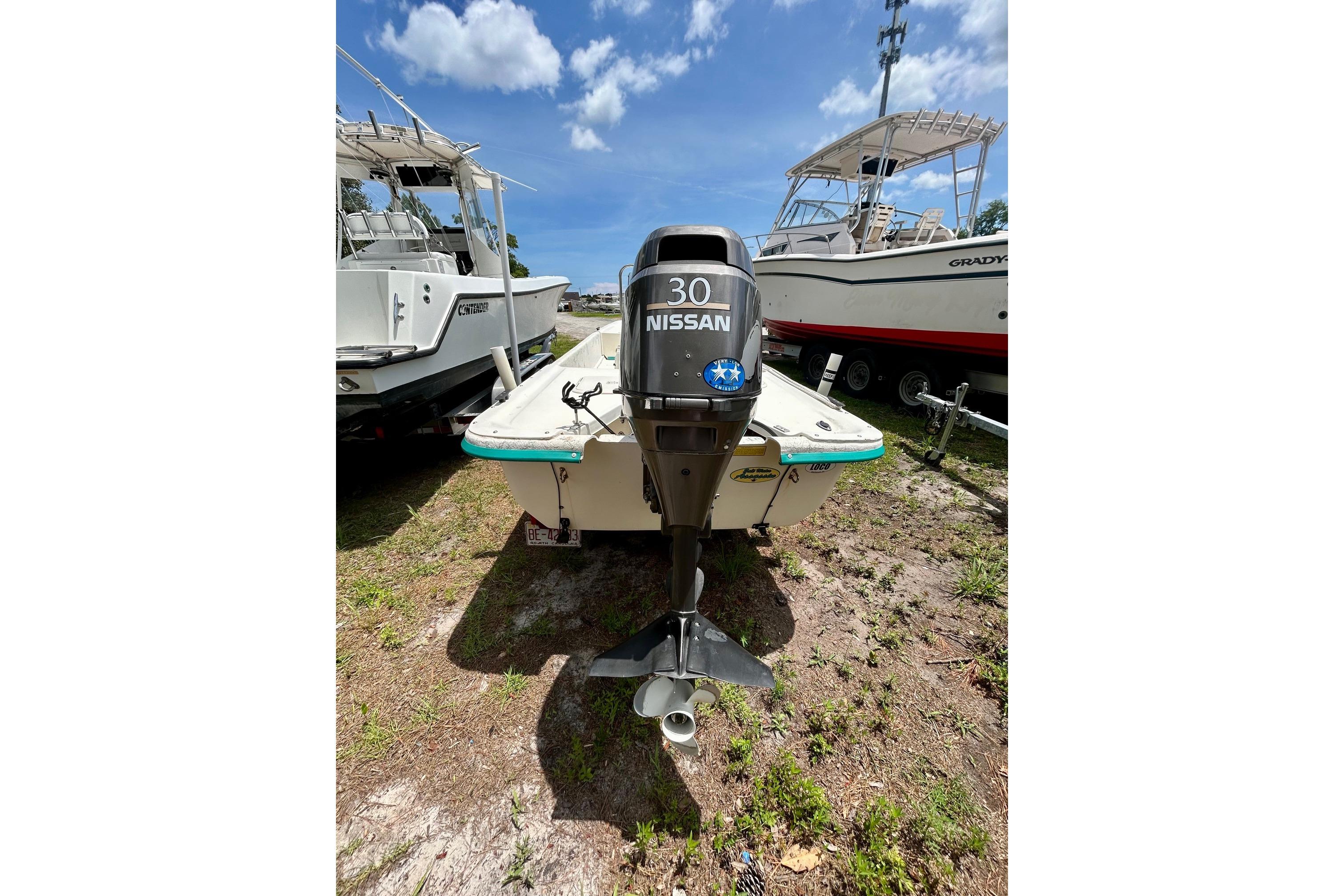 2002 Sundance K16CC boat with Nissan 30 outboard motor, parked on grass under blue sky.