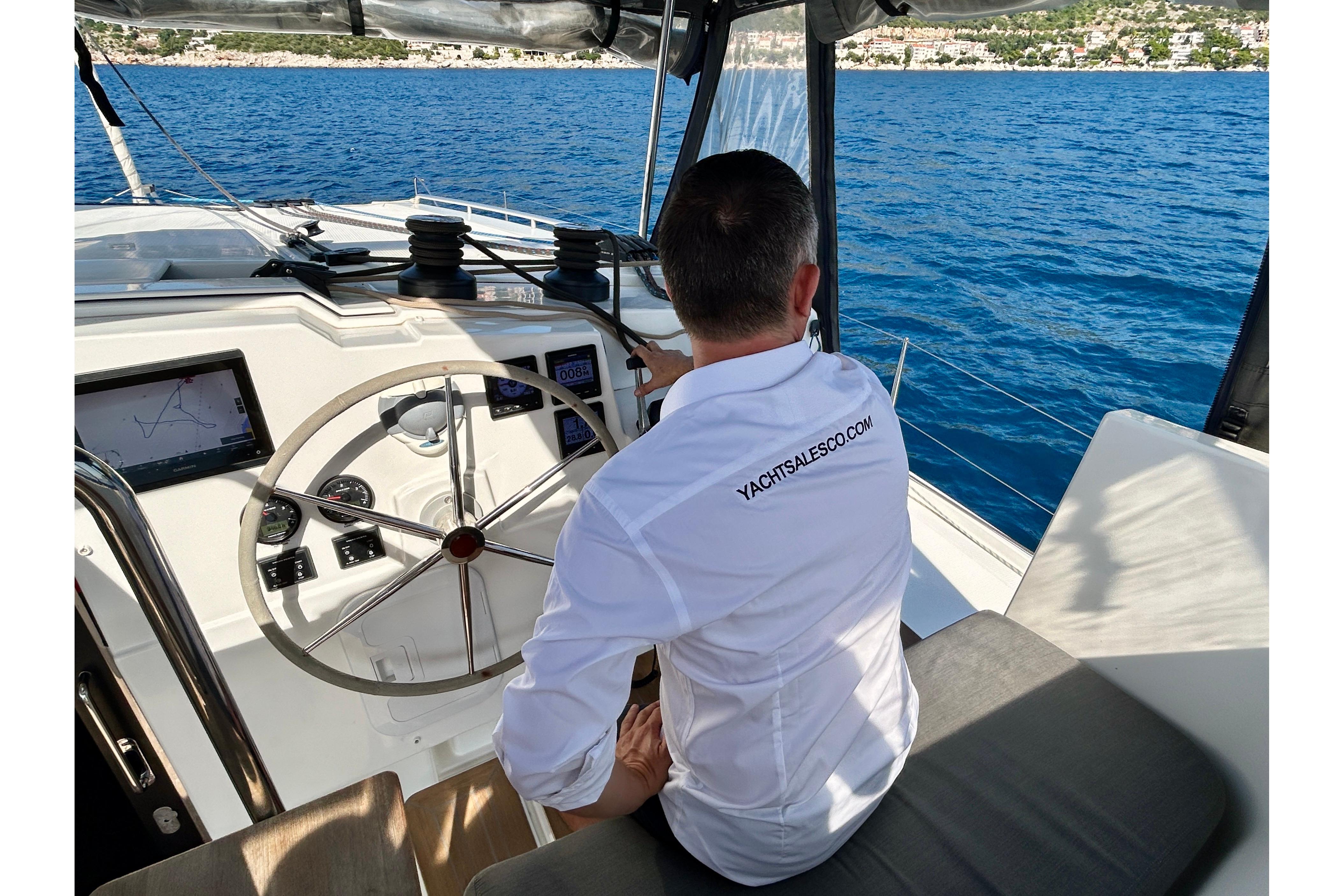 Person steering 2021 Fountaine Pajot Isla 40 catamaran on open sea.