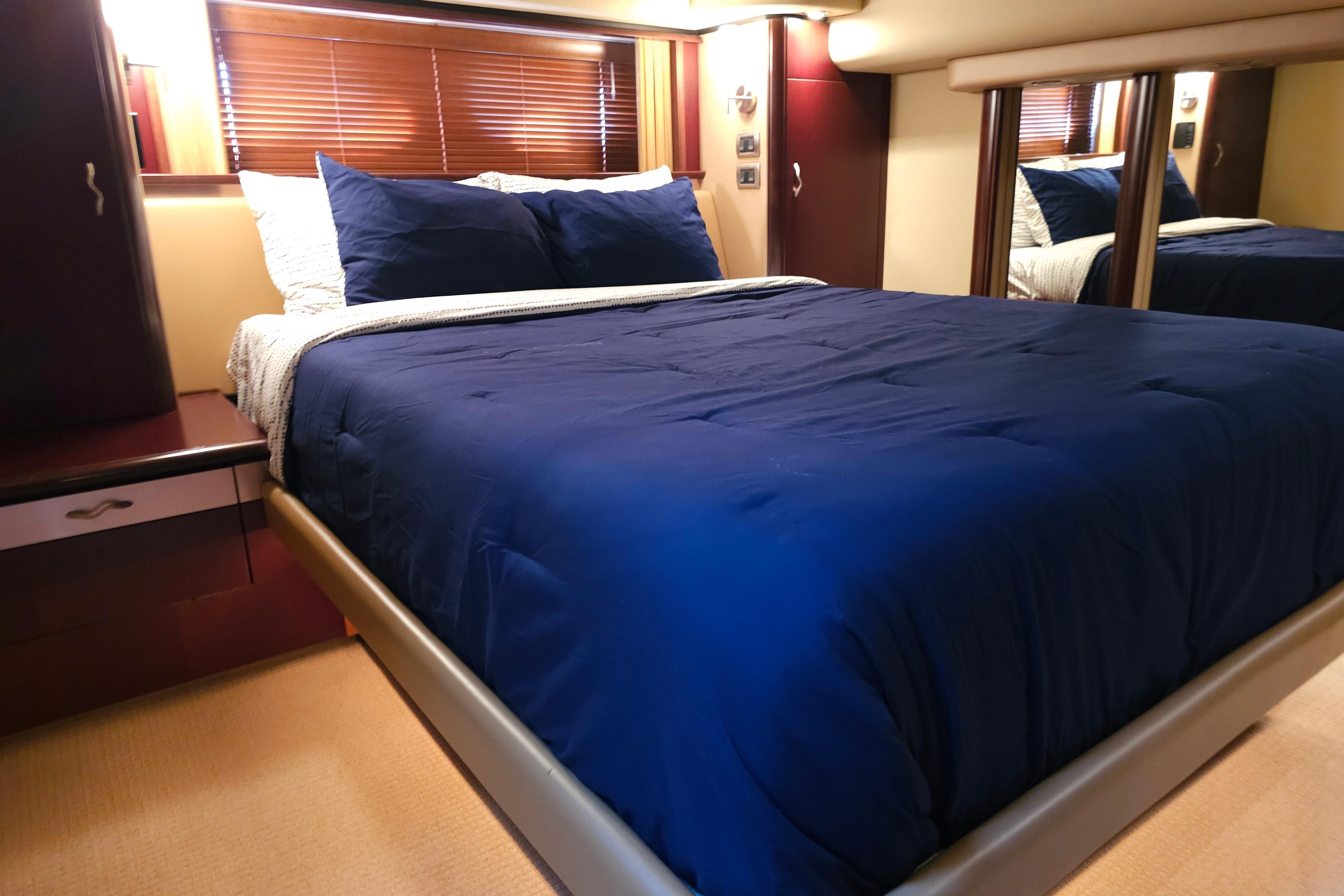 Luxurious bedroom interior of 2006 Sea Ray 580 Sedan Bridge yacht with blue bedding.