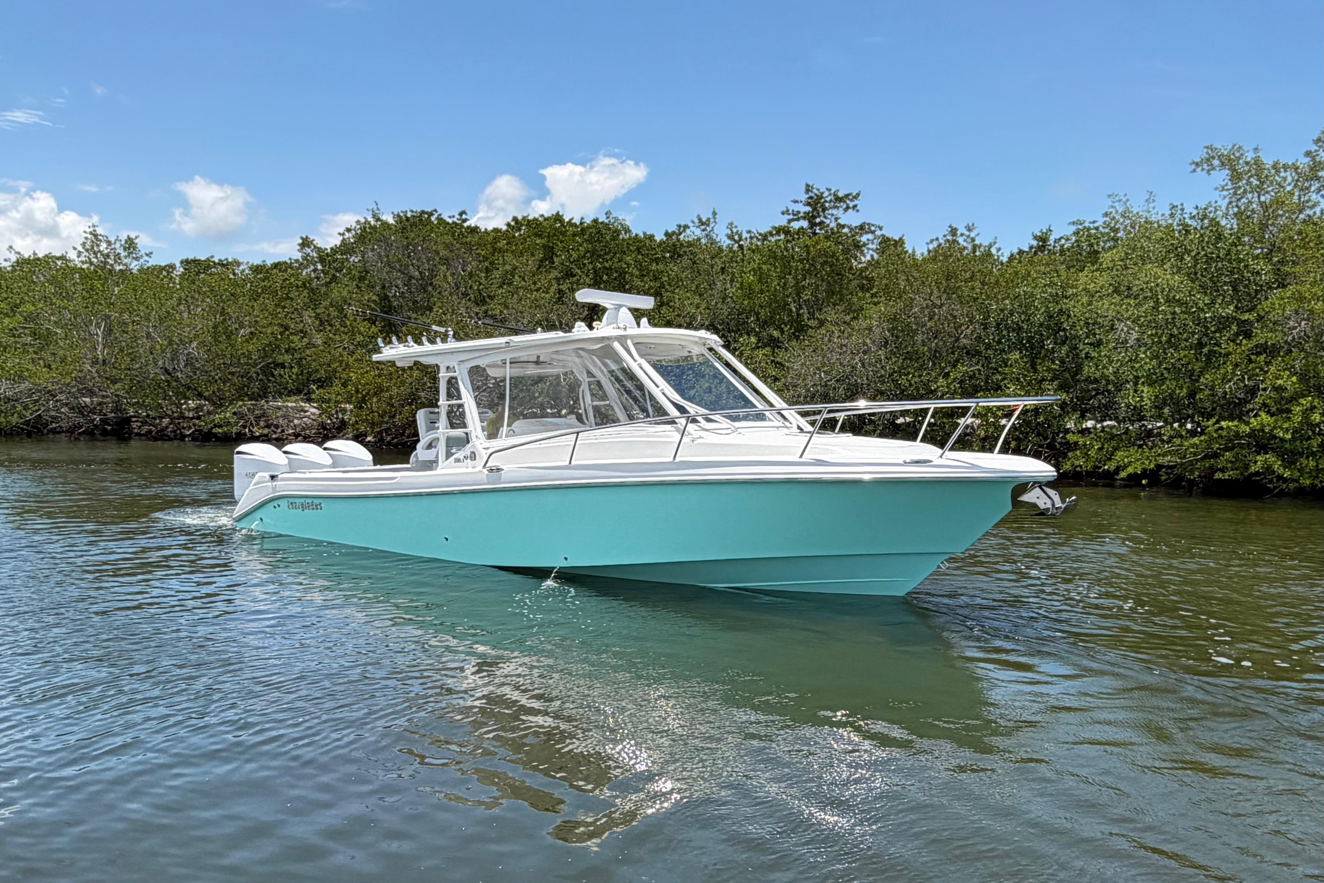 2009 Everglades 350LX boat cruising on a calm river under a clear blue sky.