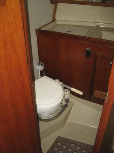 Interior view of a boat toilet with wood paneling and a sink.