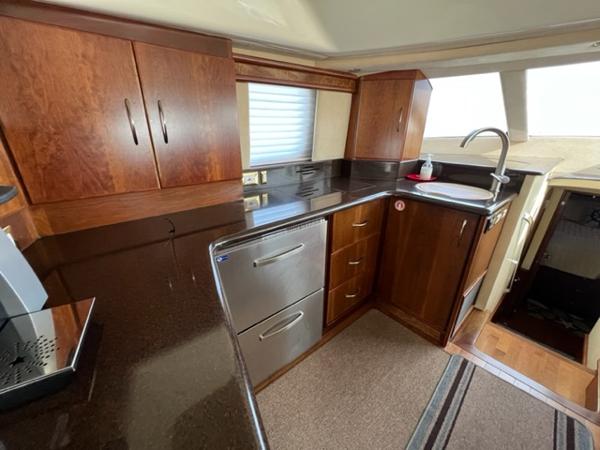 Luxurious kitchen area in a 2009 Ovation 52 yacht with modern appliances and wooden cabinetry.