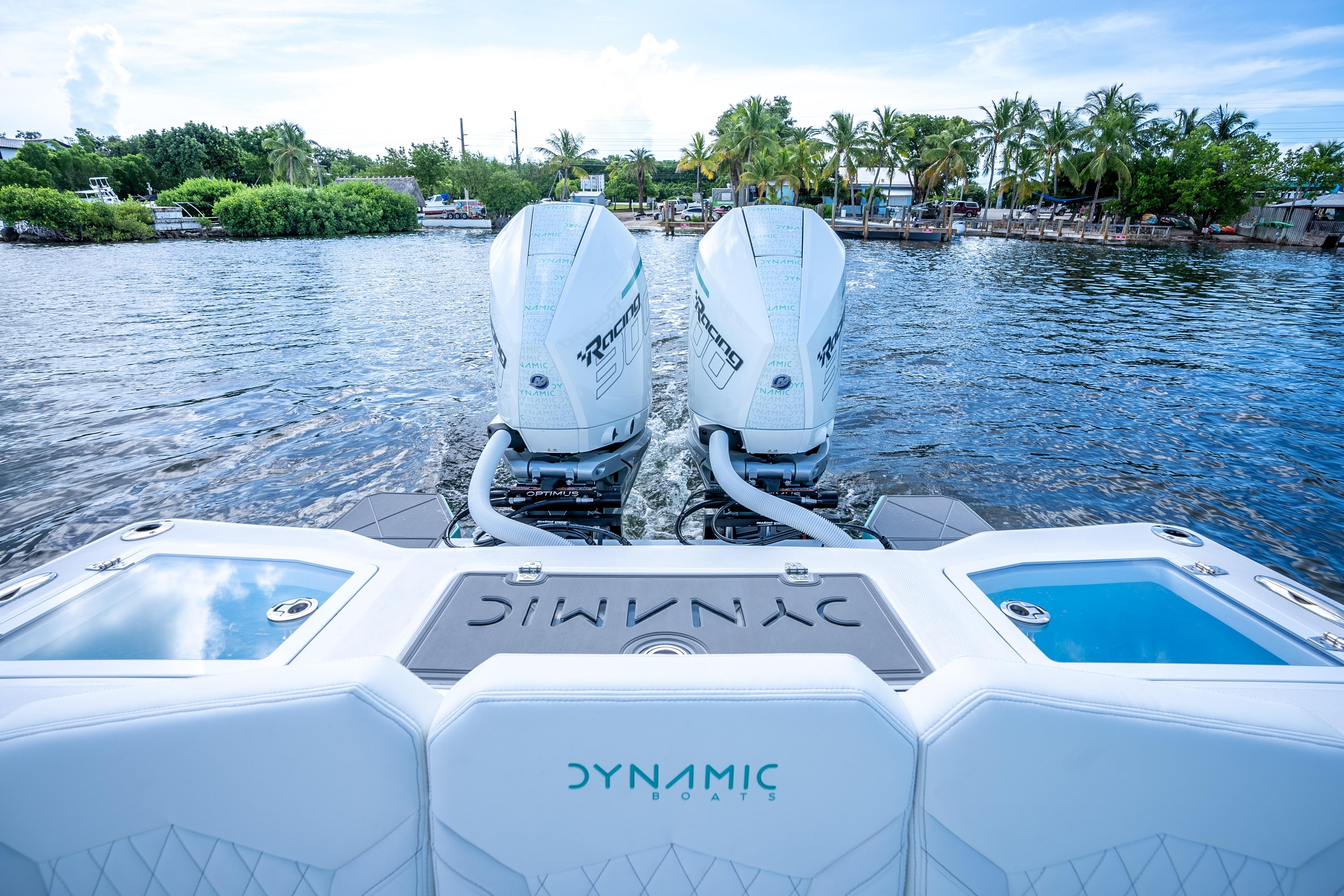 2024 Dynamic D-305V boat with twin engines on a scenic waterway.