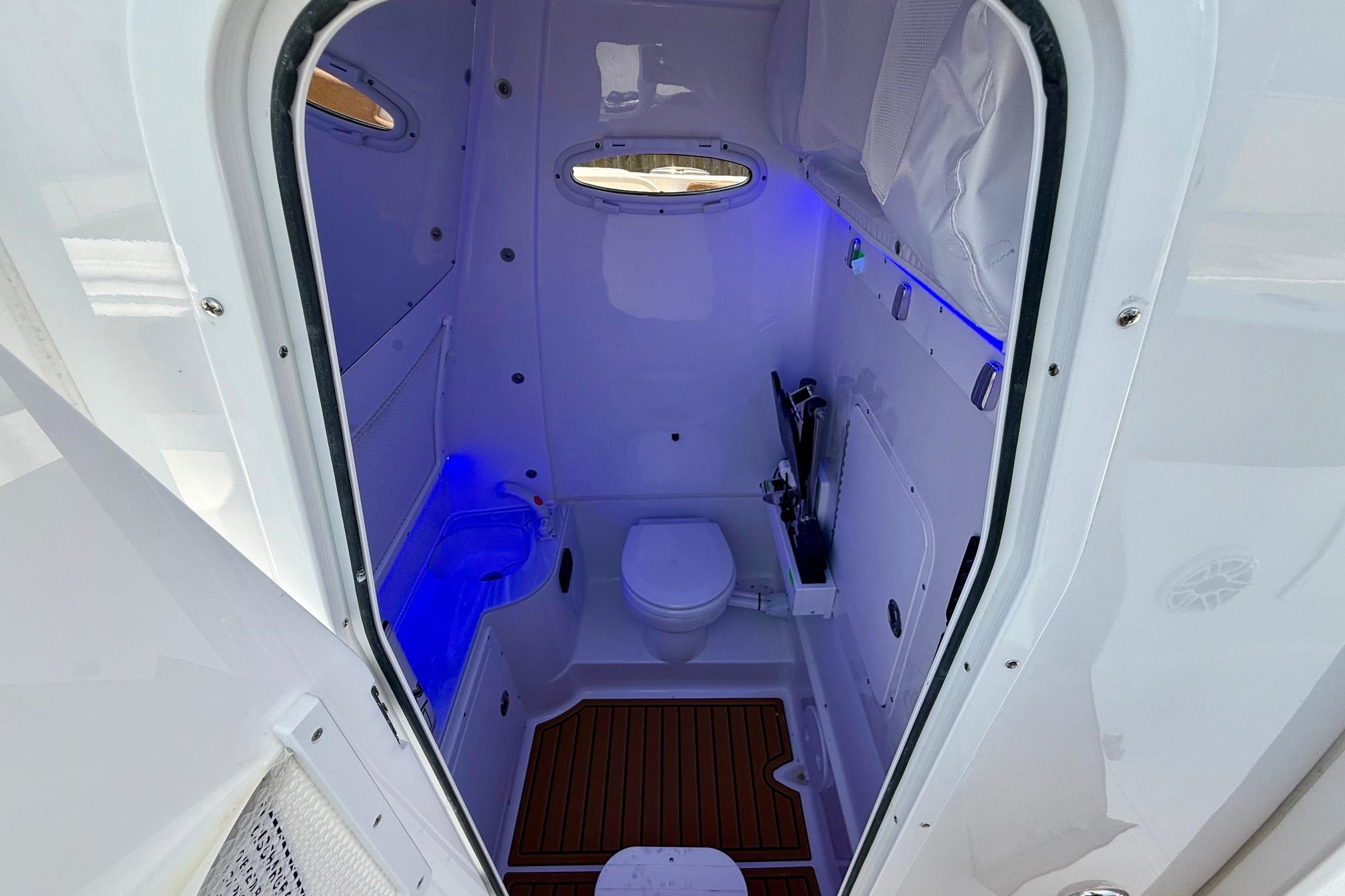 2026 Sea Hunt Ultra 305 SE boat interior with modern bathroom and blue LED lighting.
