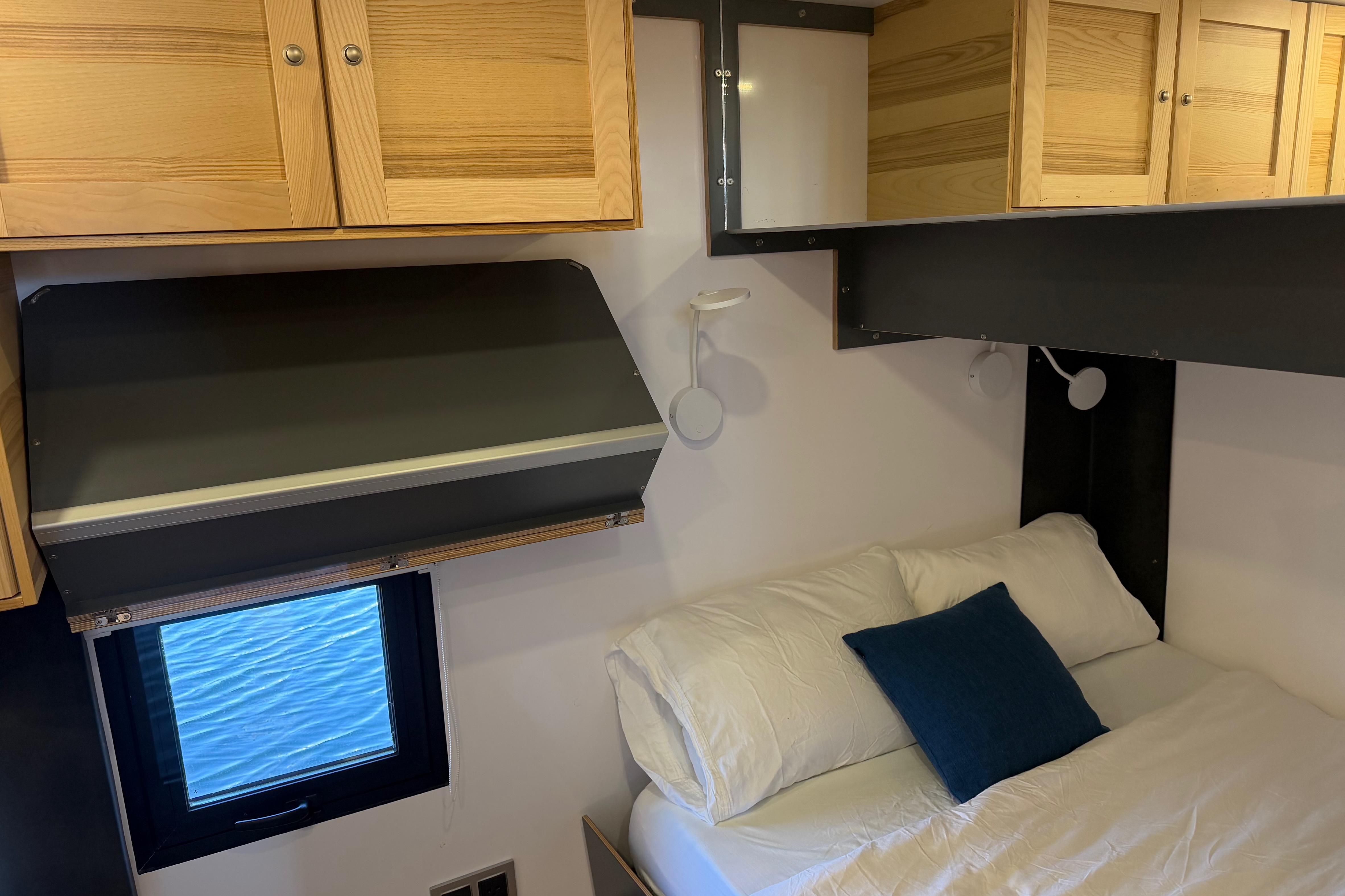 Cozy interior of 2022 Navisyo NV.08 with wooden cabinets and a comfortable bed.