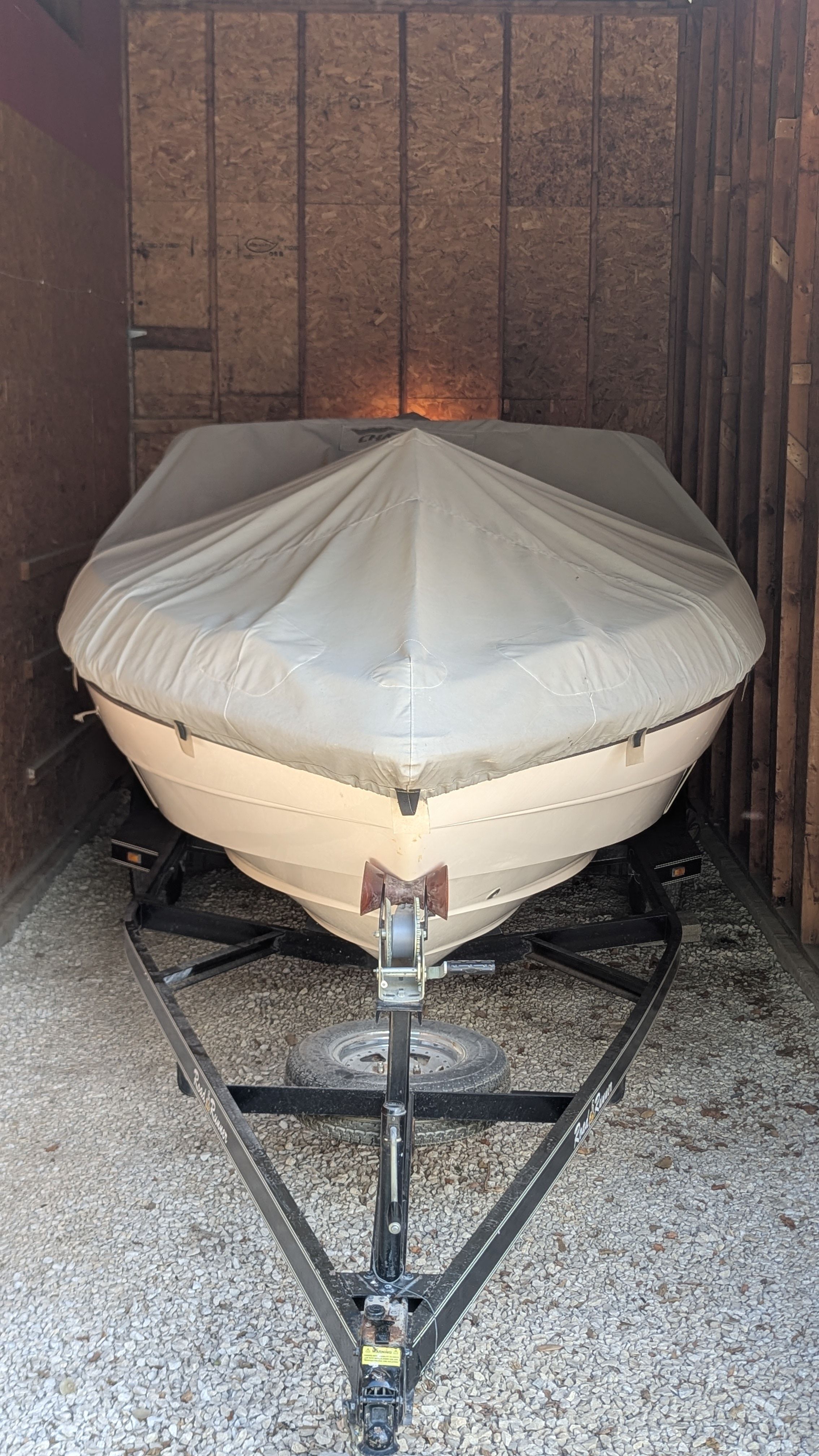 A 2000 Chaparral 240 SSi boat, covered and stored on a trailer in a shed.