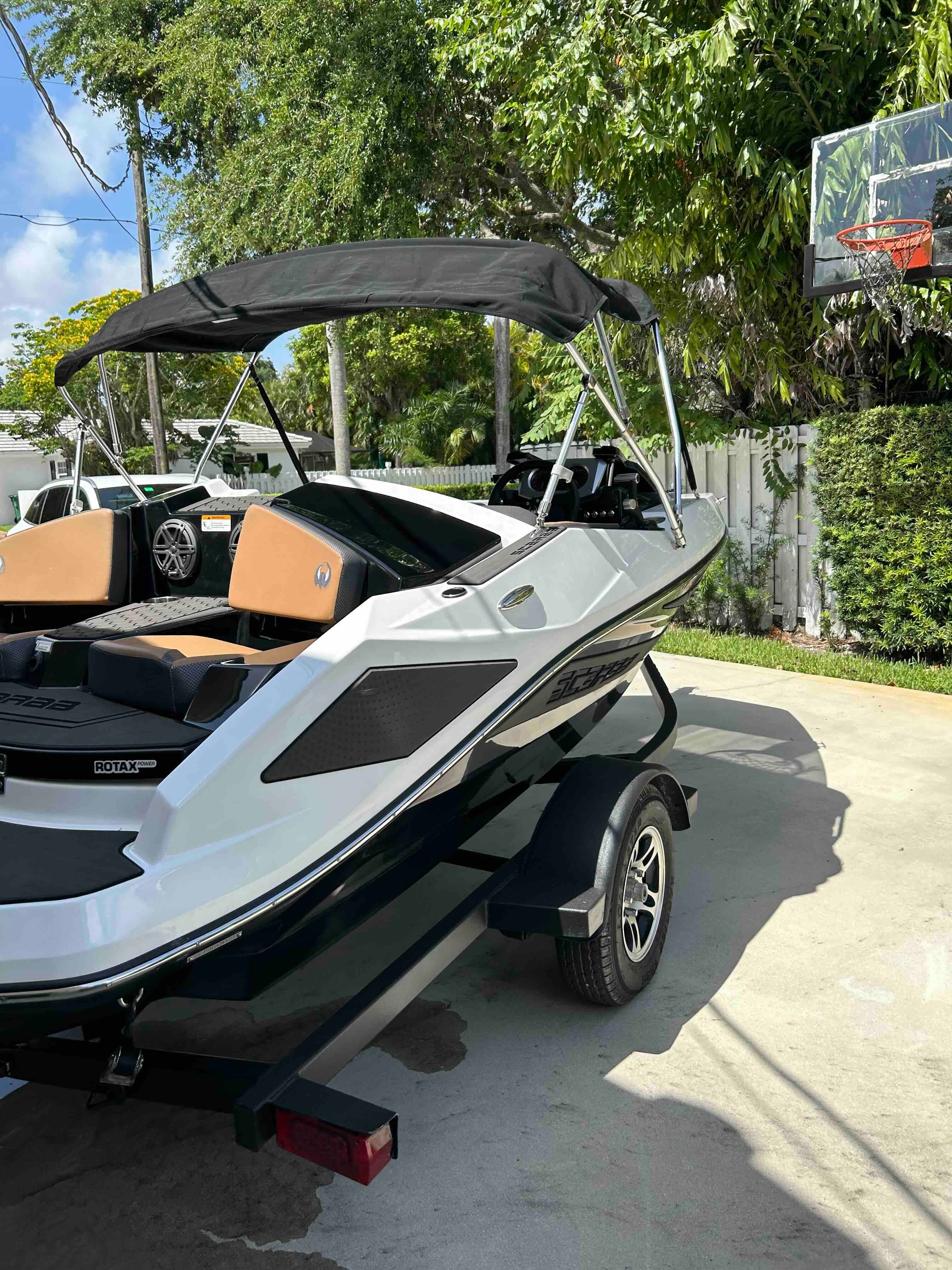 A 2022 Scarab 165 ID boat on a trailer in a sunny yard.