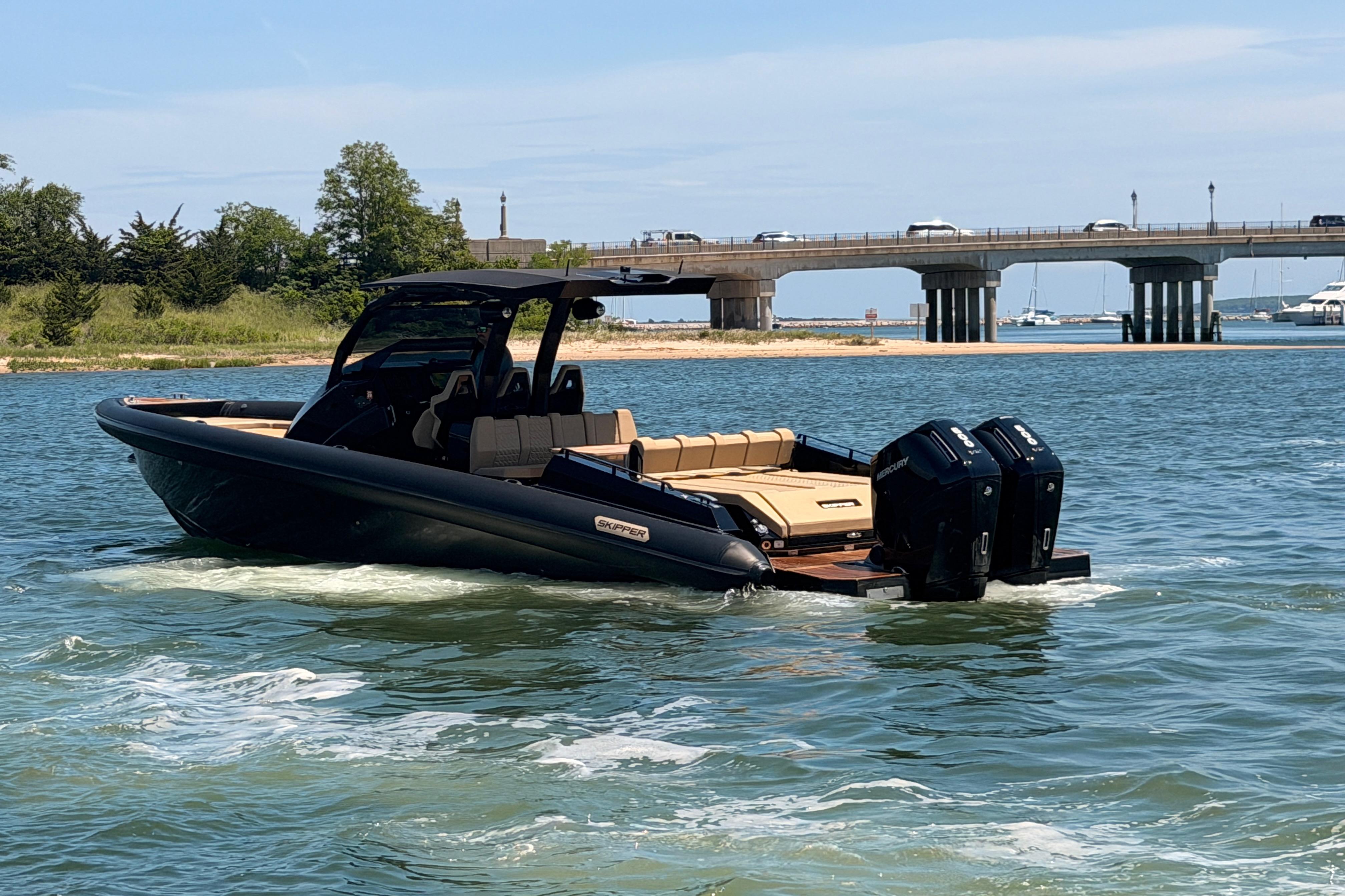 2023 Skipper-BSK 42NC boat cruising near a bridge on a sunny day.