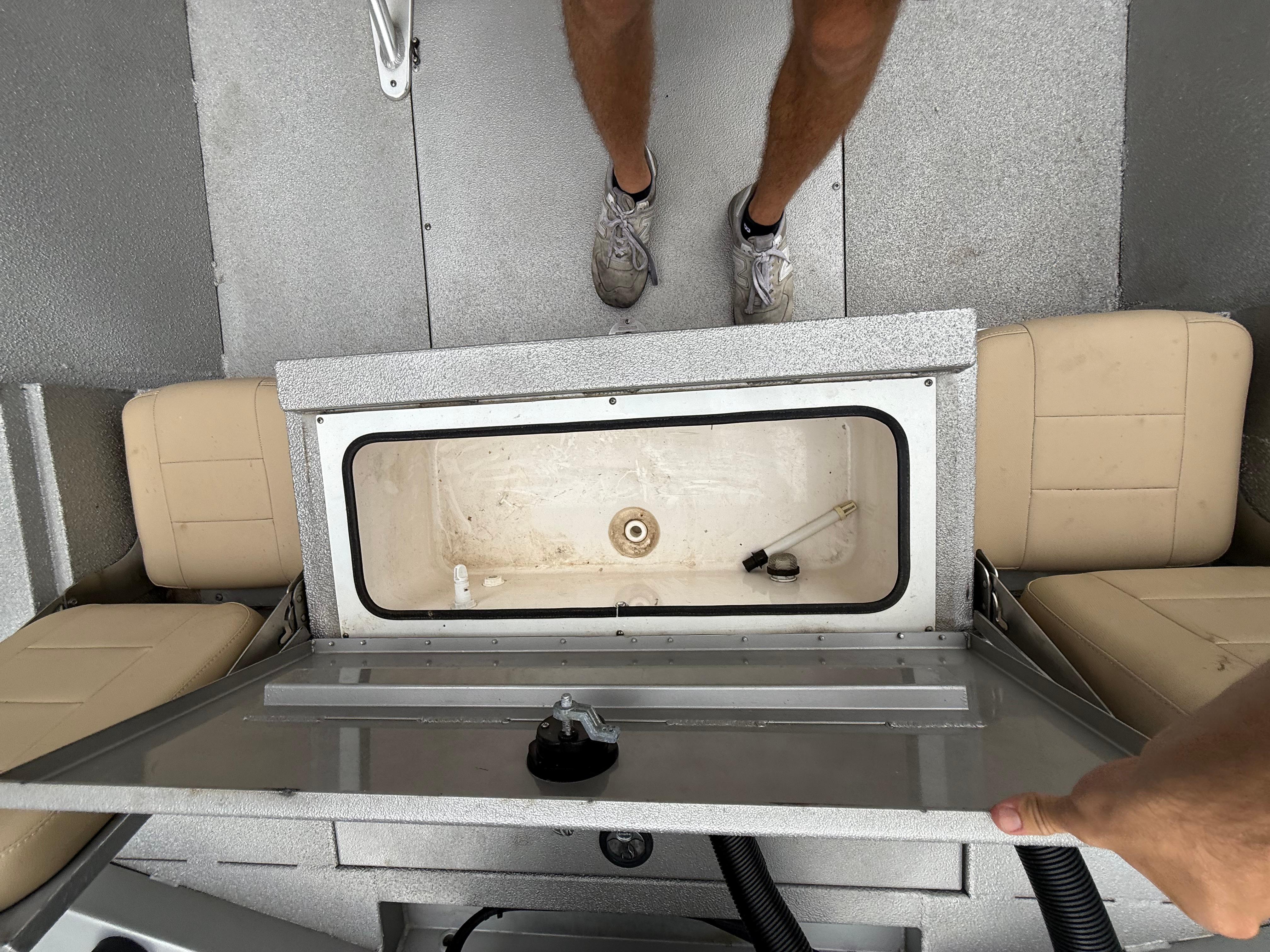 2020 Avid 23 FS Platinum boat interior with open storage compartment and beige seats.