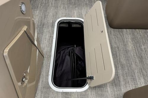 2026 Bennington 22SXSB boat storage compartment with open hatch on carpeted floor.
