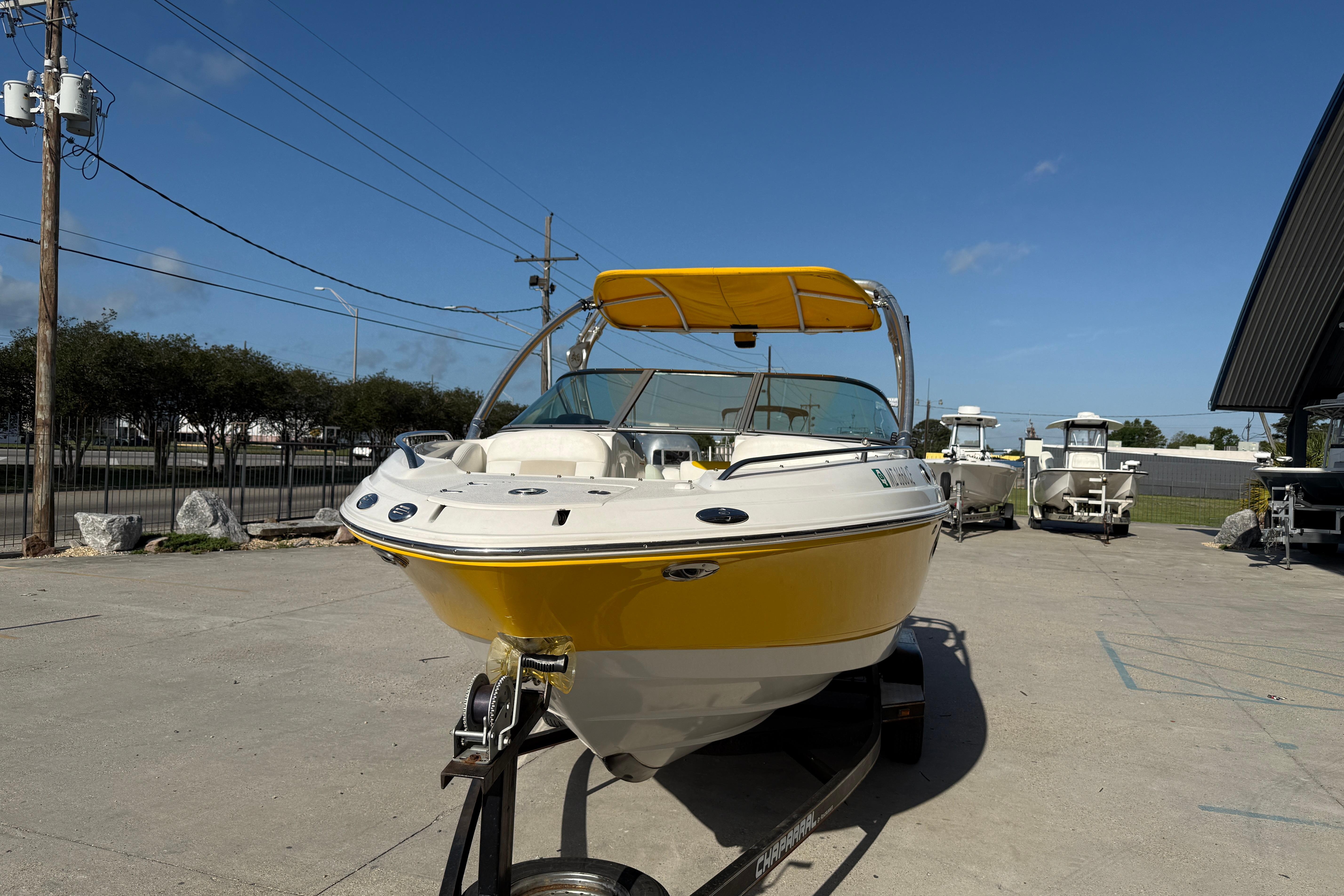 2008 Chaparral 236 SSX boat with yellow hull on trailer, parked outdoors.